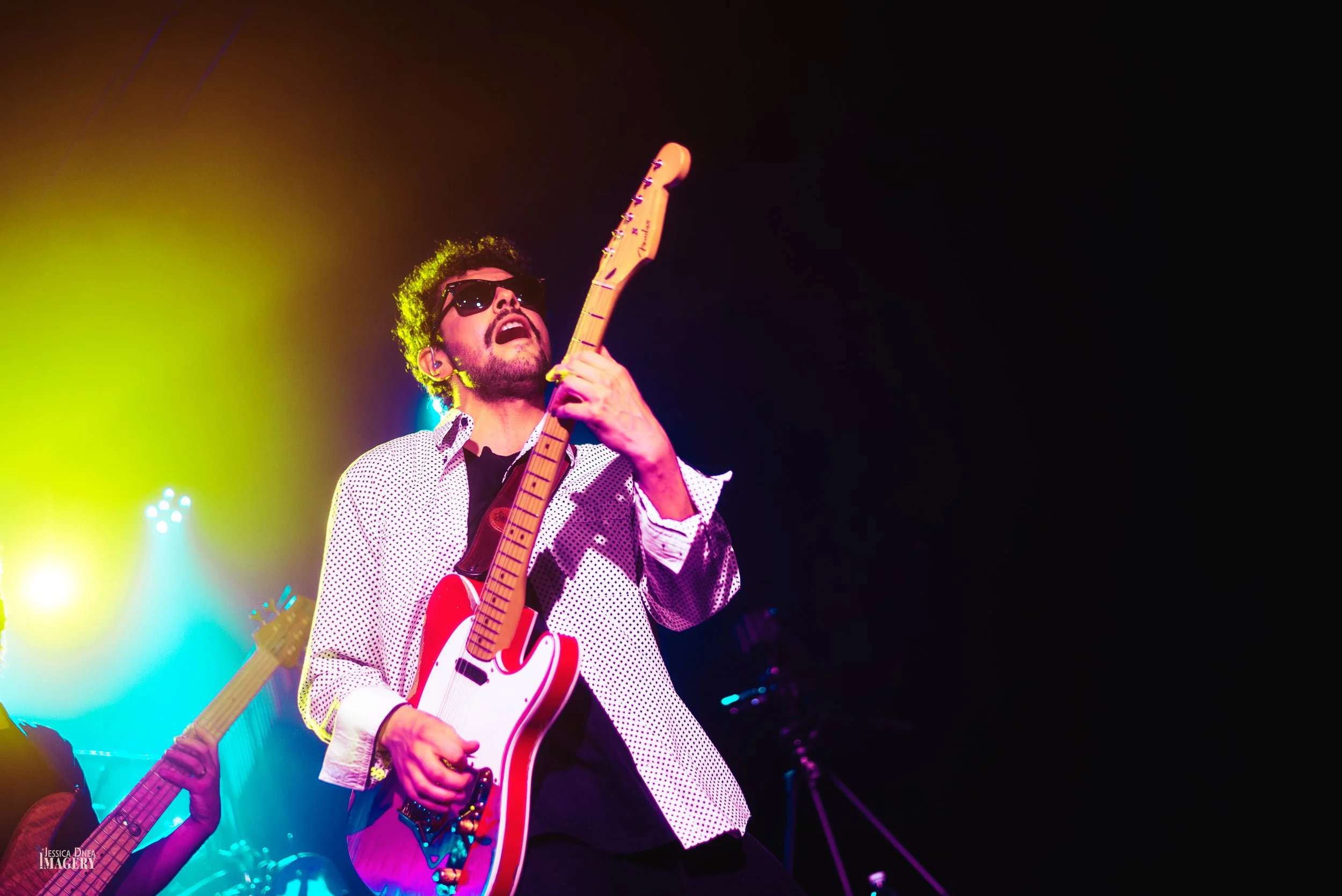 The Hip Snacks guitarist performs in sunglasses beneath vivid red, yellow and green lighting during a live concert at Cervantes in Denver.