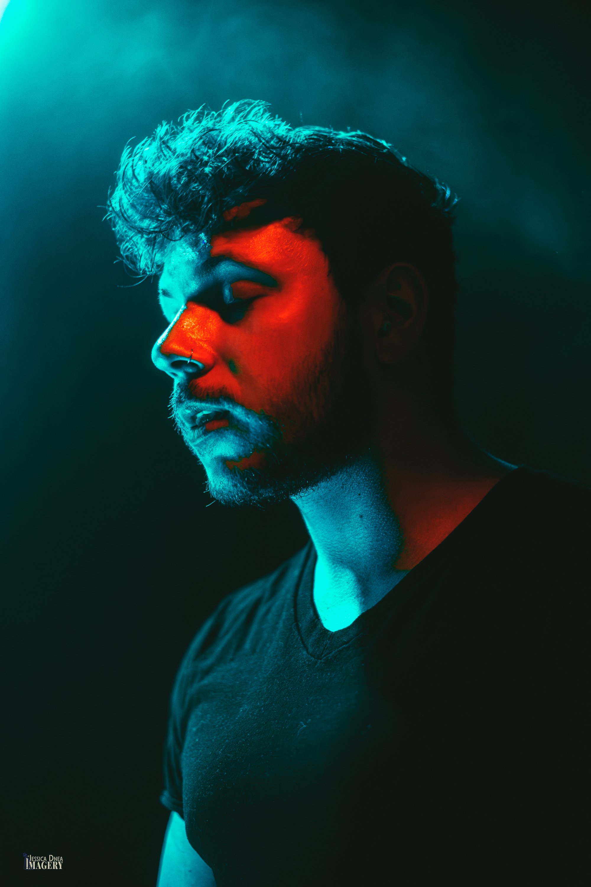 A Phooey musician appears in a dramatic side-profile portrait divided by turquoise and red concert lighting at Lost Lake in Denver.