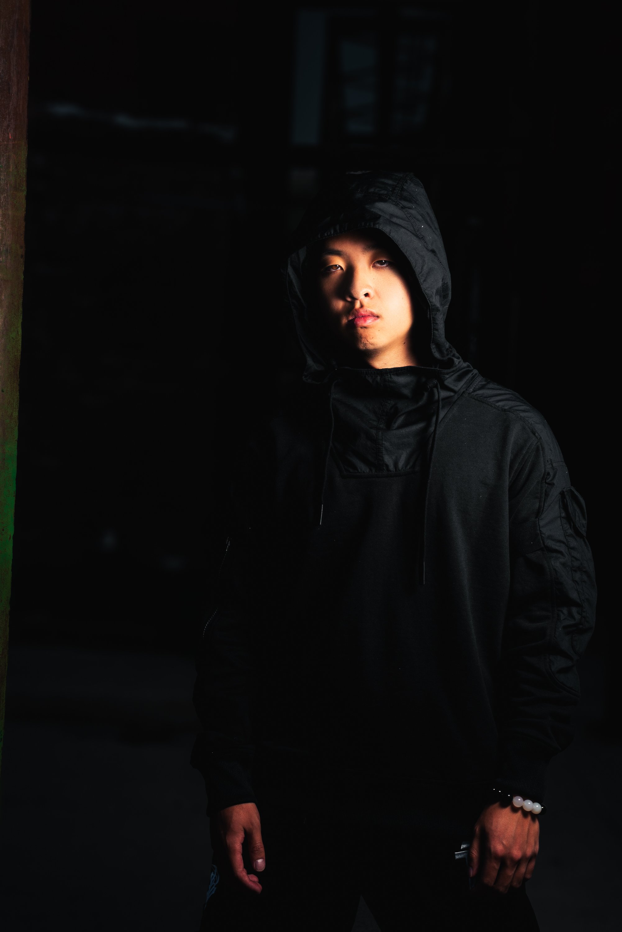 Dark editorial artist portrait in a hooded outfit created for EPKs, music press and promotional materials.