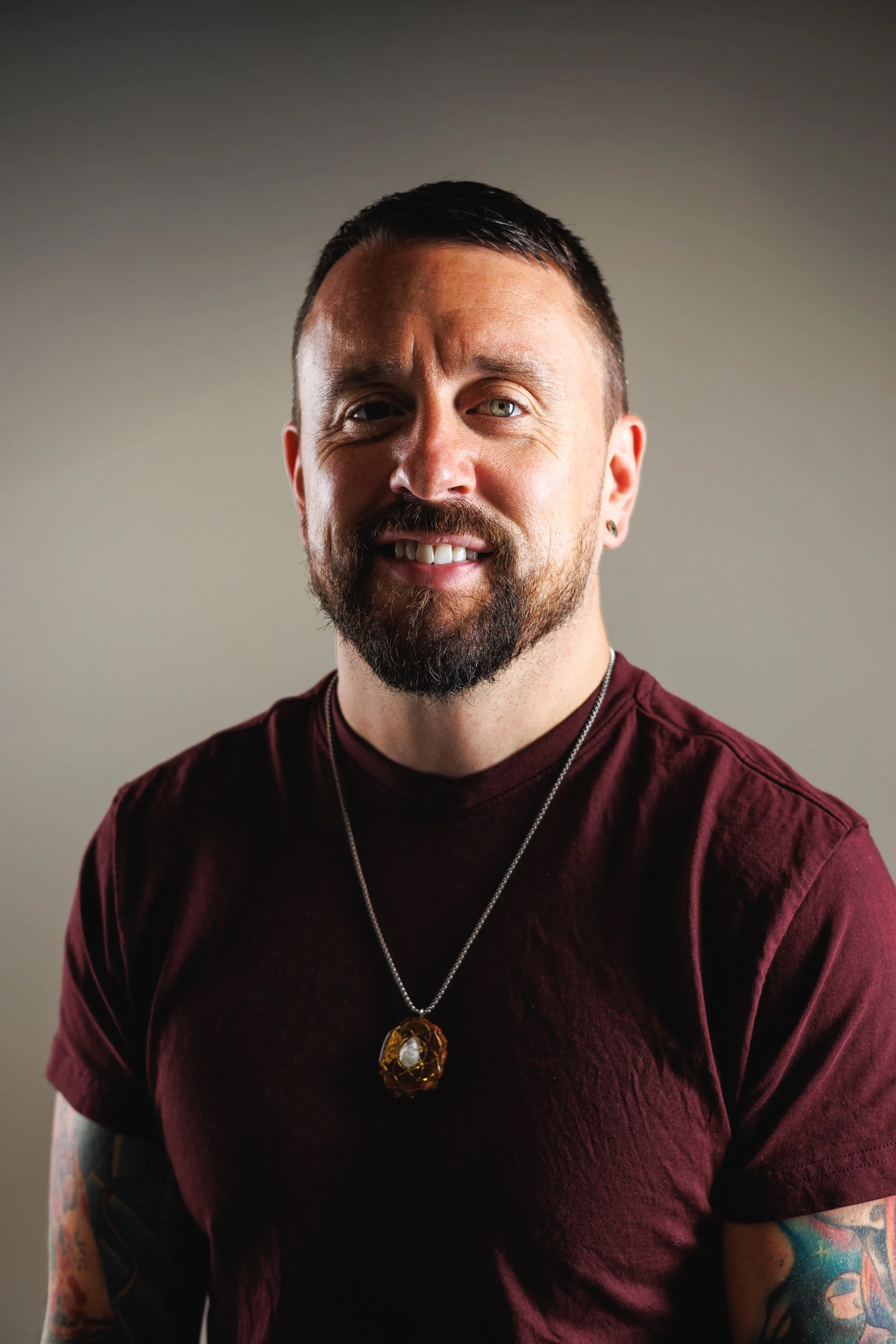 Friendly close-up branding headshot of a bearded professional in a maroon shirt by Denver photographer Jessica Dnea Imagery.