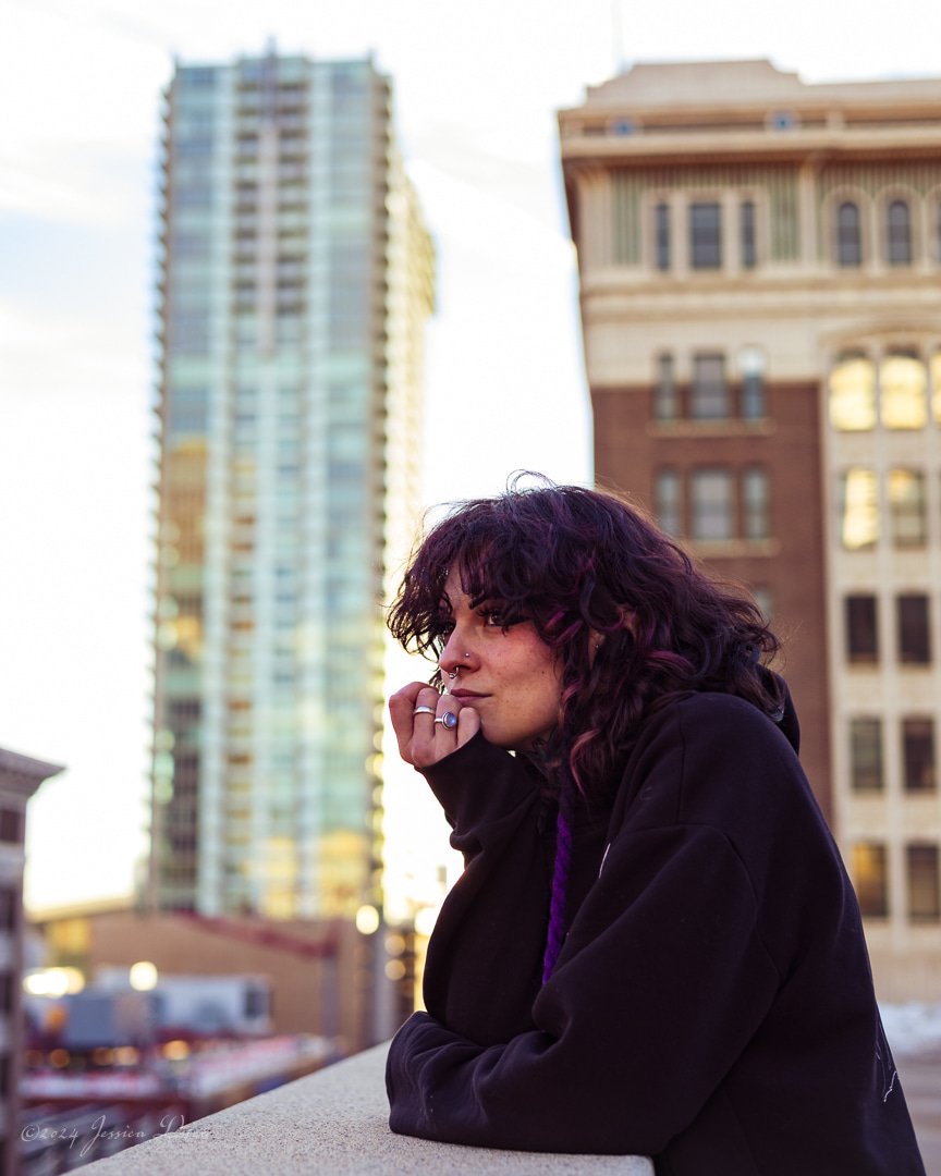 Thoughtful outdoor branding portrait of a tattoo artist leaning against a rooftop wall by Denver photographer Jessica Dnea Imagery.