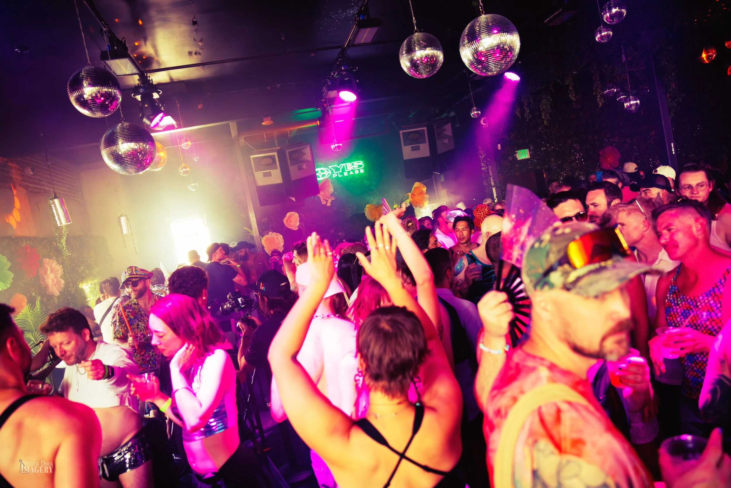 A packed Denver Pride dance floor moves beneath disco balls, pink lighting and colorful club decor during a Boogie Lights performance.