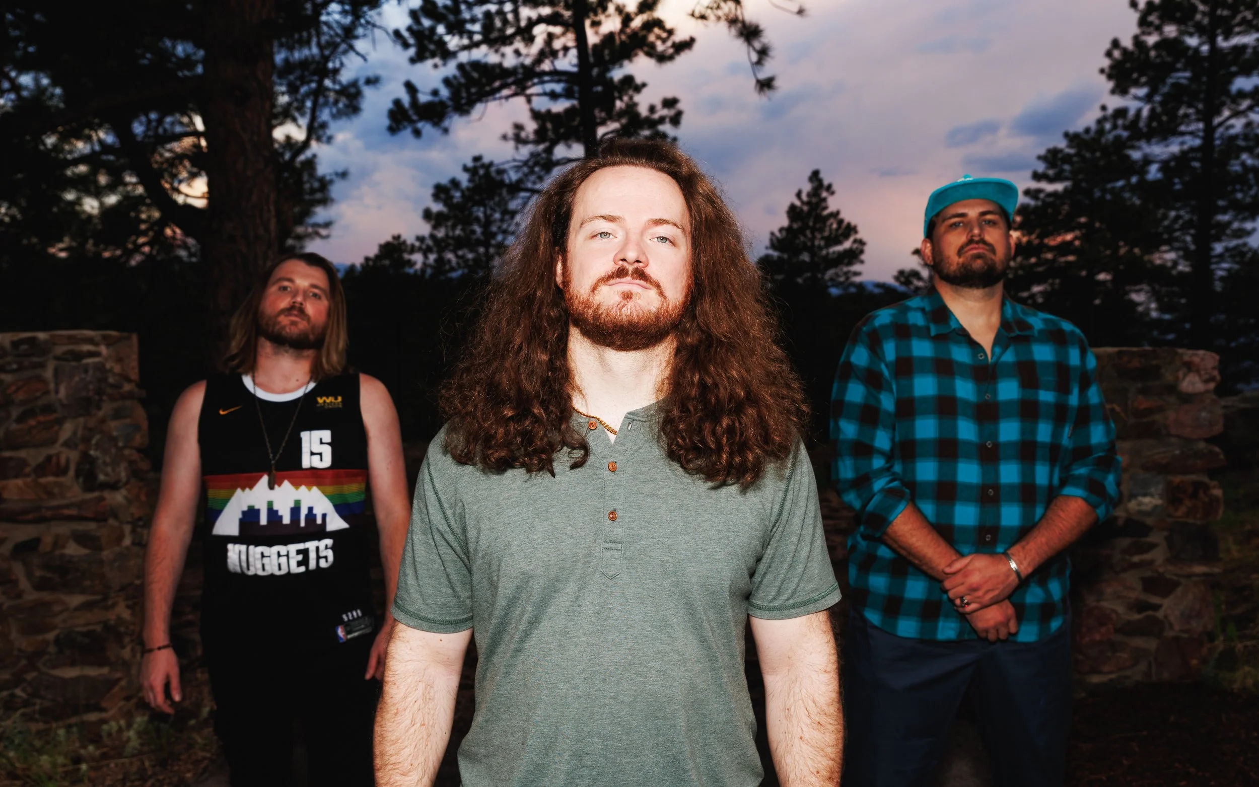 Outdoor band promo photo of RADO posed among pine trees at dusk for EPK, booking and music promotion.