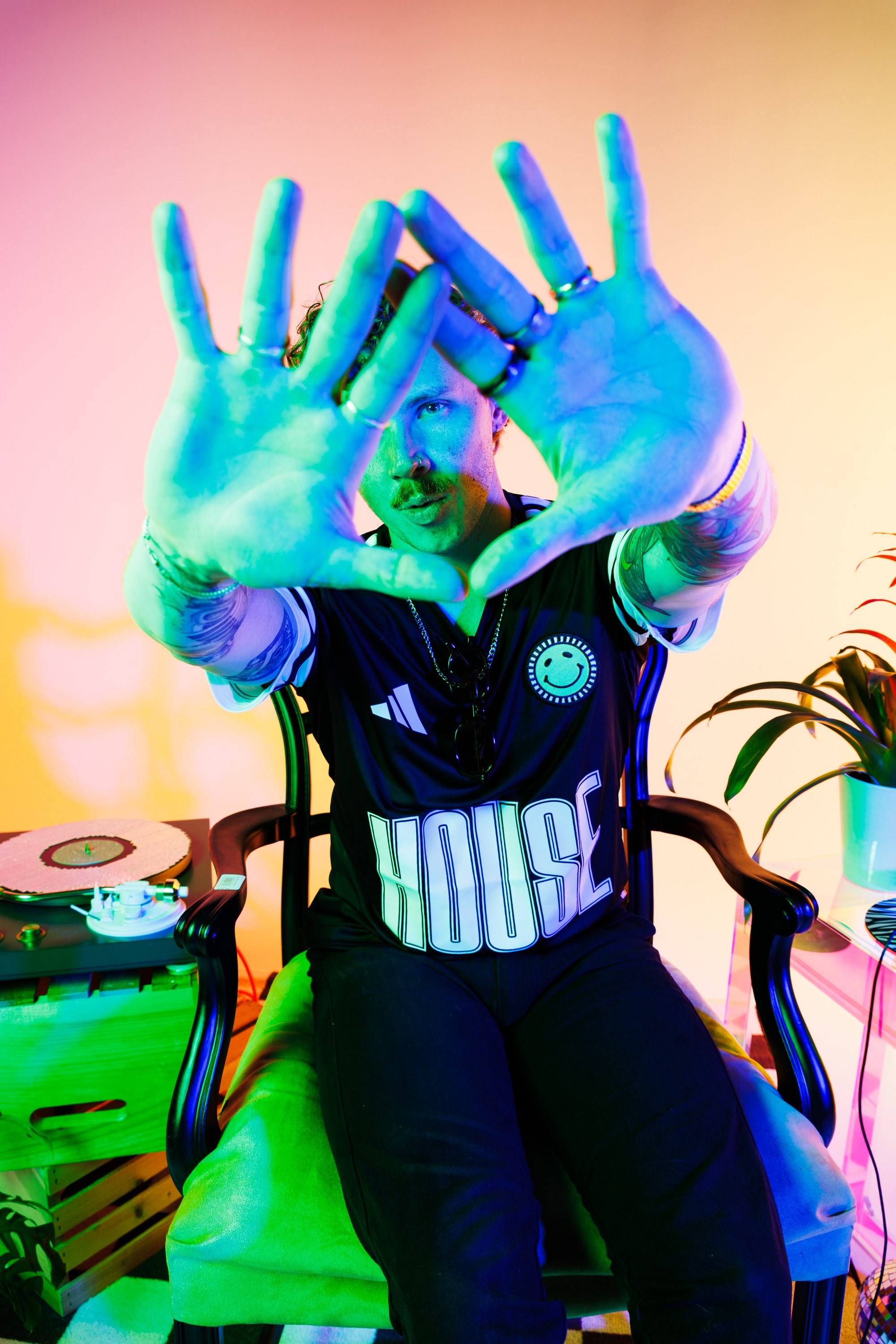 Bold Denver musician press portrait with saturated green, blue, pink, and yellow lighting, playful hand placement, and colorful creative direction for artist promotion and releases.