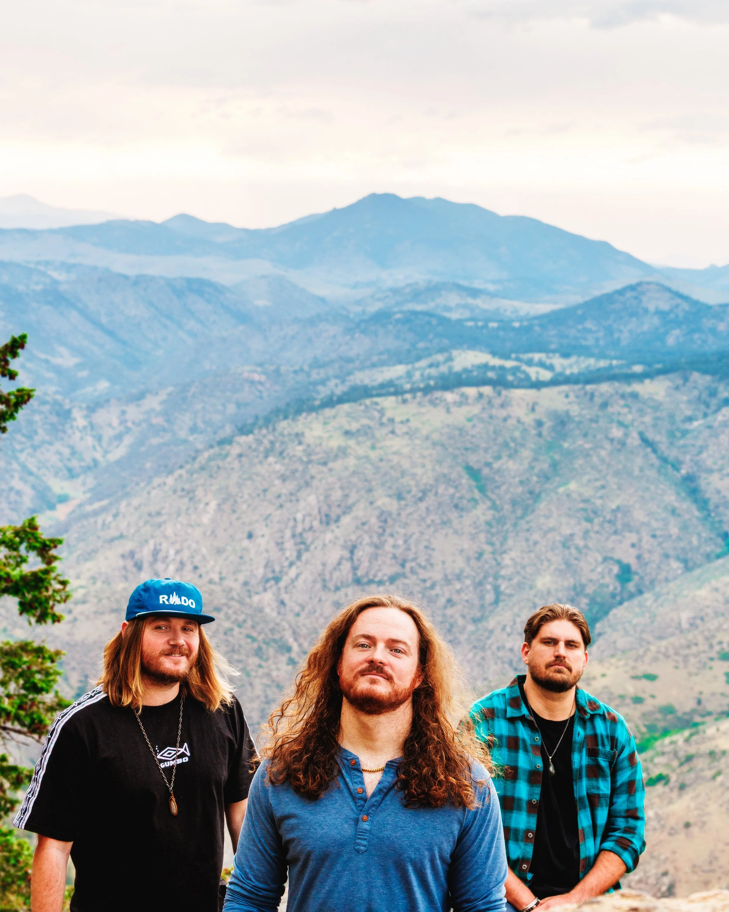 Three-member creative team posed against Colorado mountain scenery during an outdoor branding session by Denver photographer Jessica Dnea Imagery.