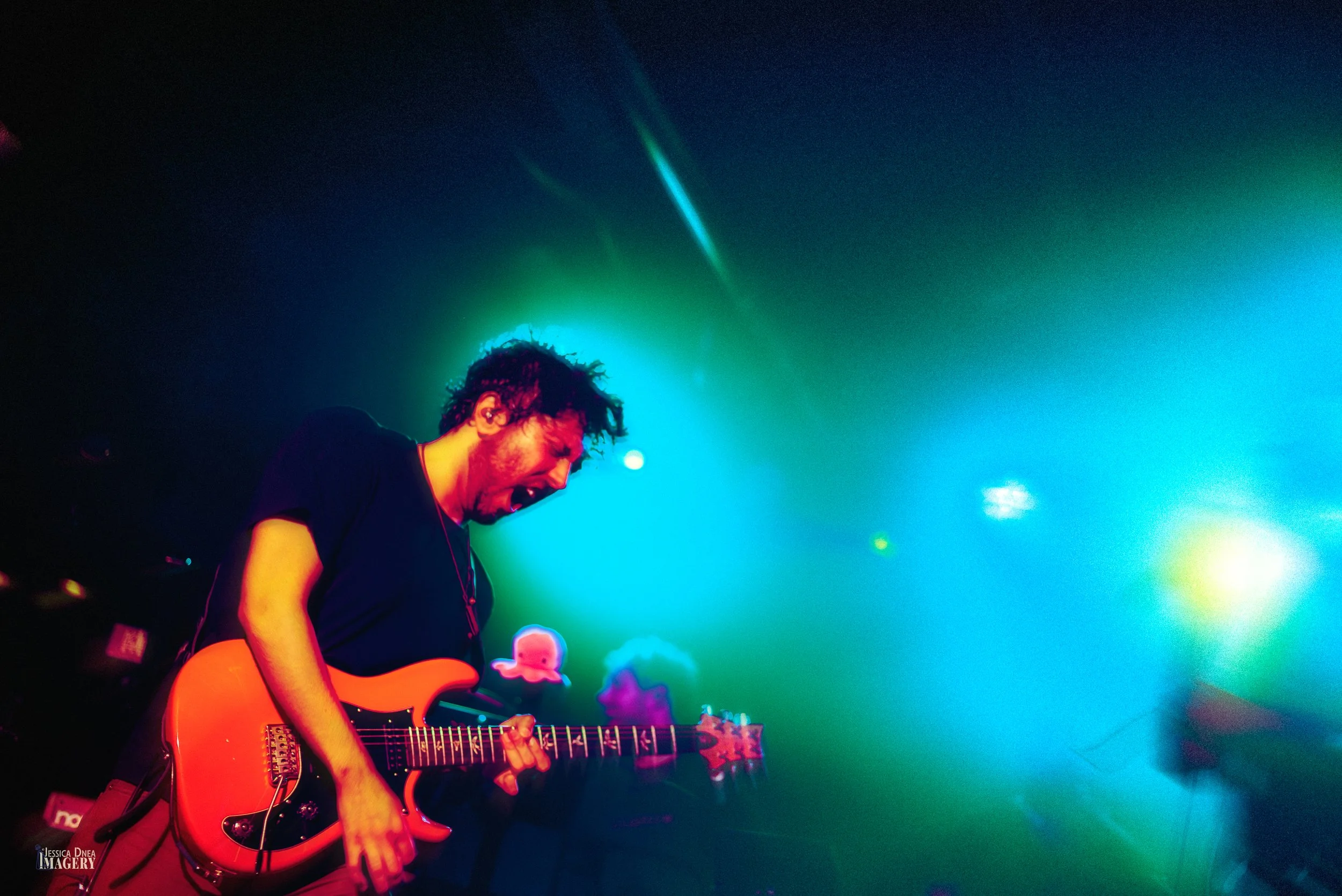 The Hip Snacks guitarist performs beneath turquoise, green and yellow lighting during a live show at Cervantes in Denver.