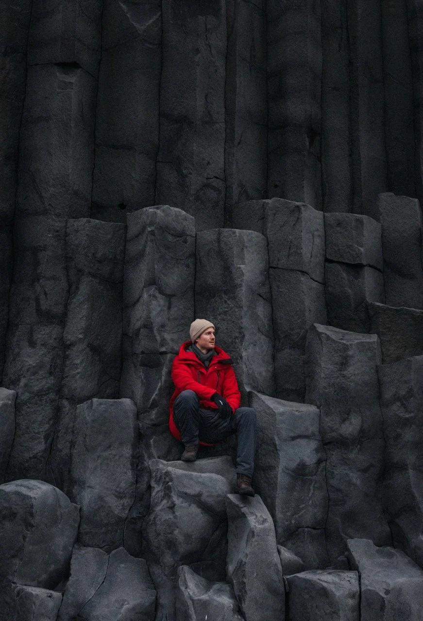 couple stopping to take photos at blacksand beach in from of basalt columns in iceland
