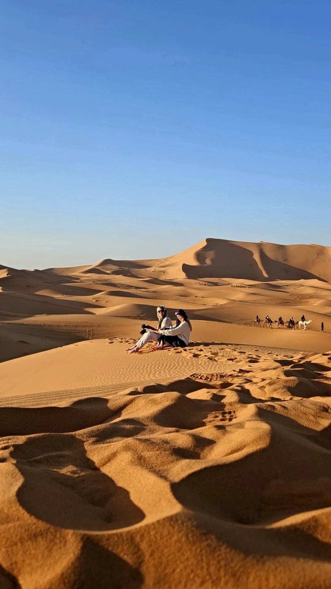 Couple walking through sand dunes in the Sahara Desert