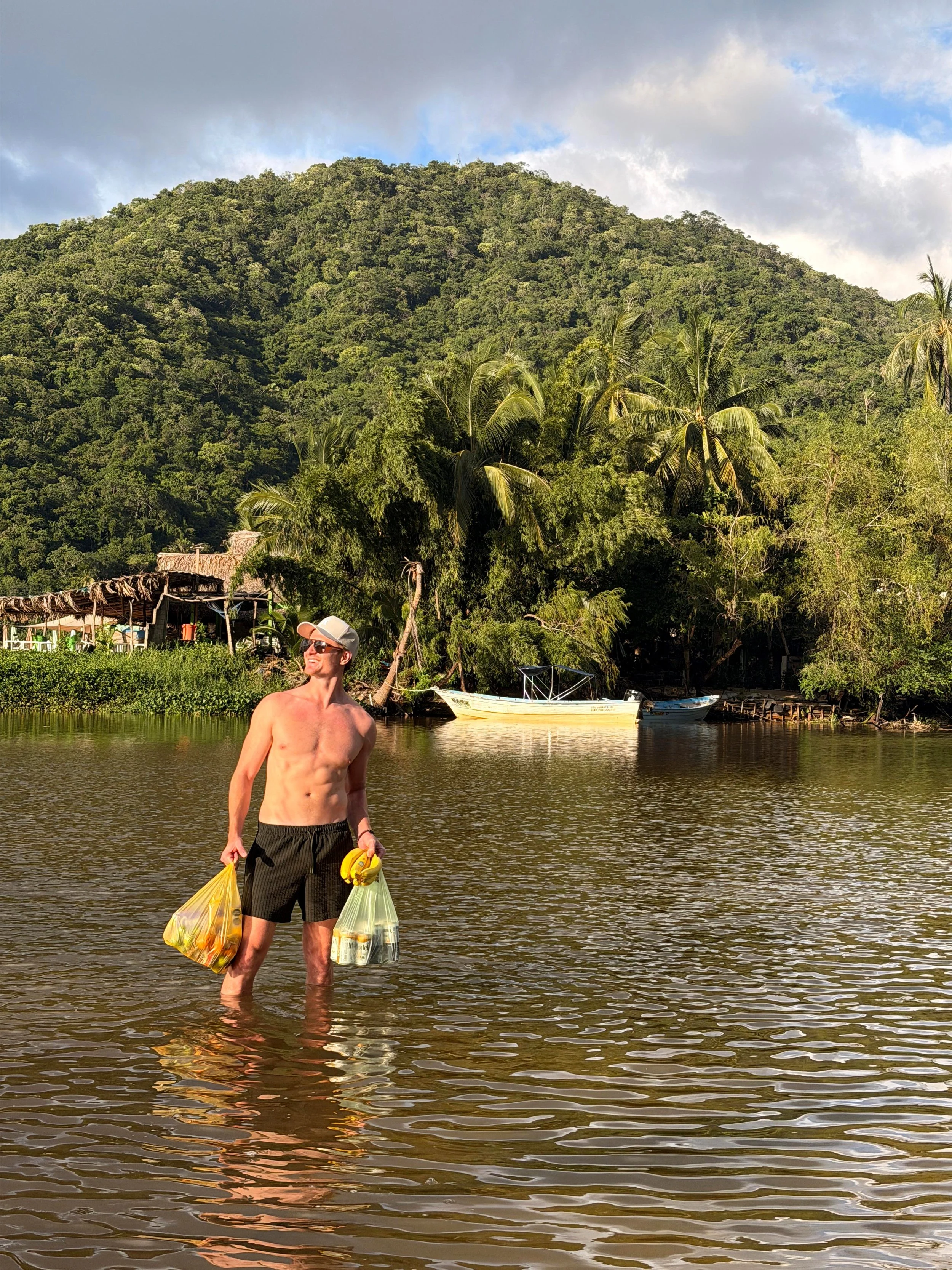 Man wading through the river with this shopping in yelapa mexico