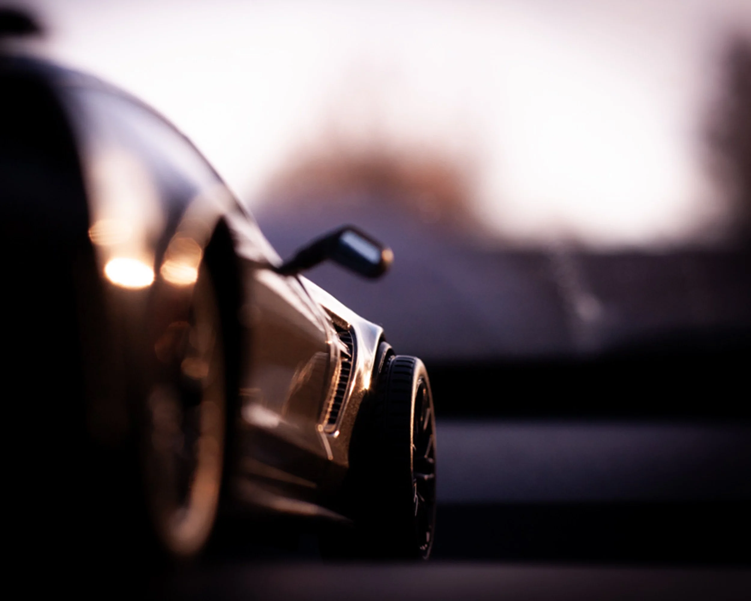 Close-up of a toy car, focusing on its wheel and side mirror, with a blurred background.