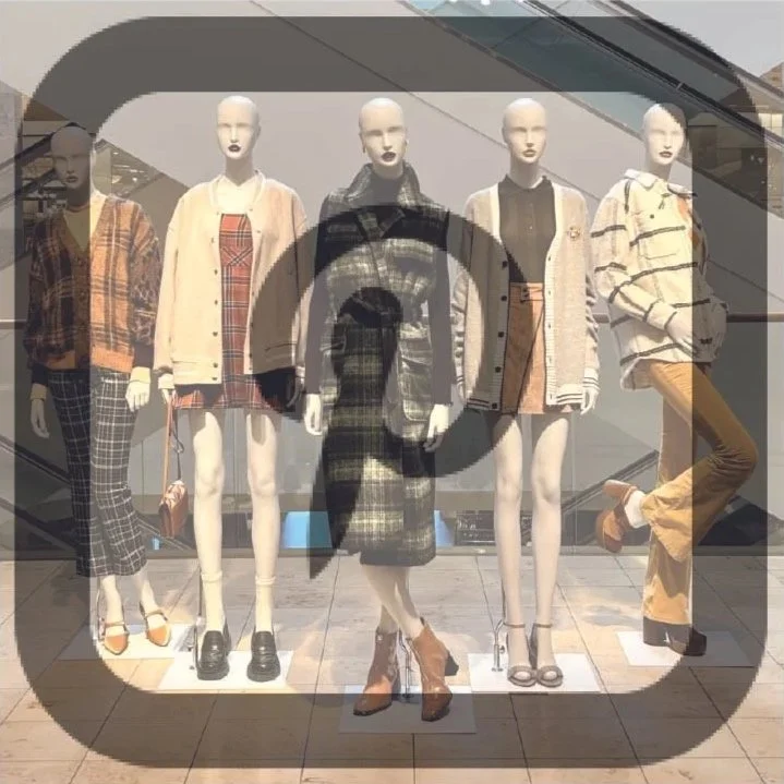 Display window featuring five mannequins dressed in stylish fall and winter clothing, with a mixture of patterns and neutrals.
