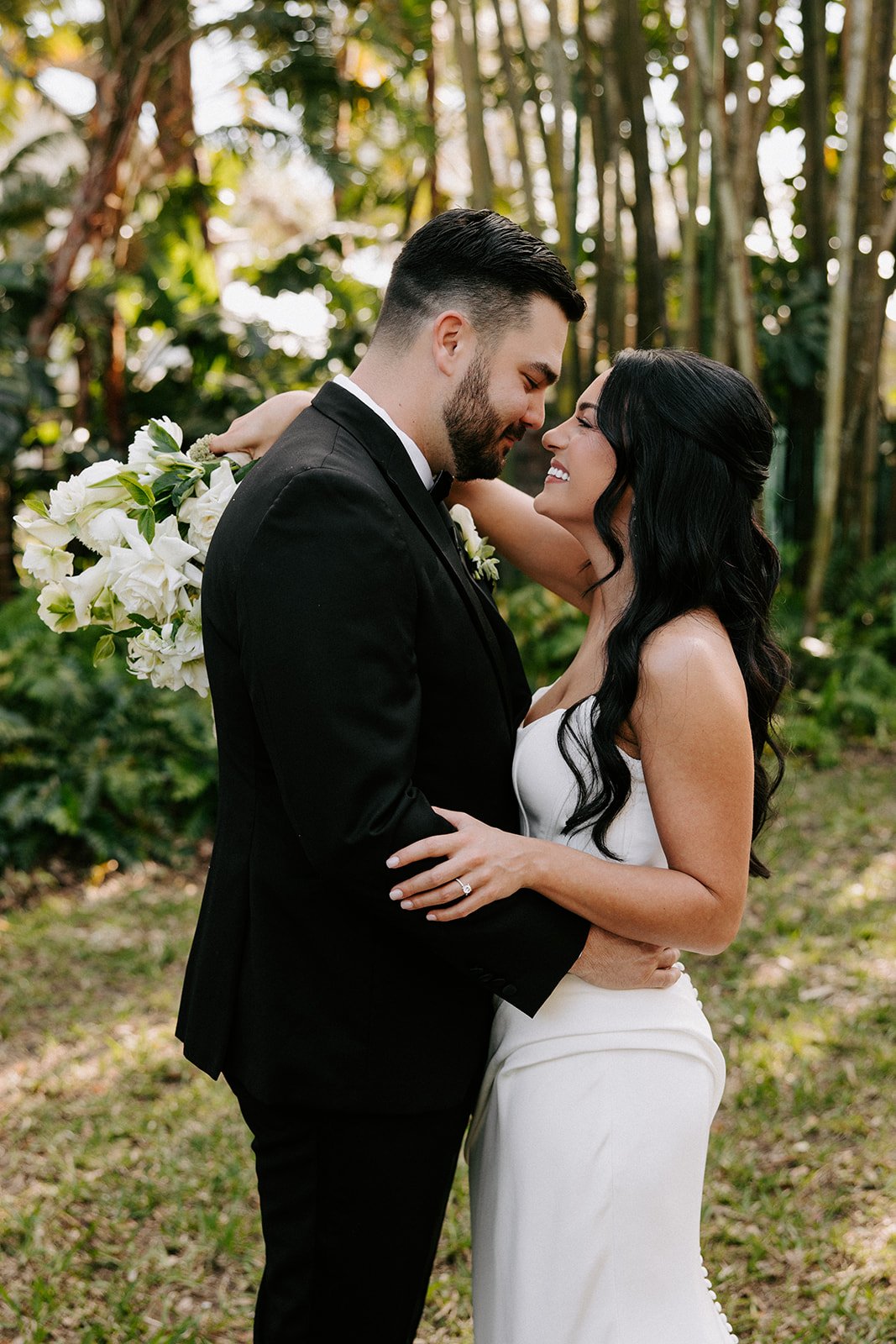 Bride and groom embracing outdoors with green foliage background