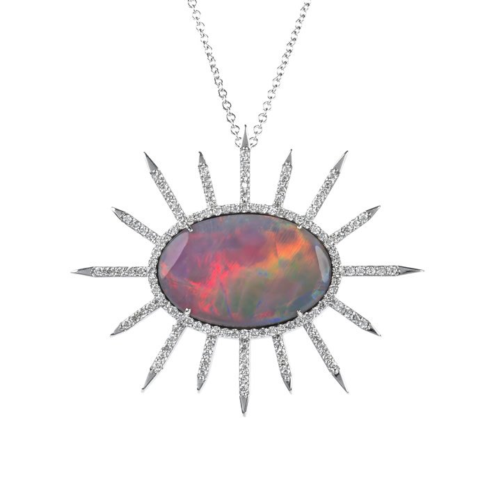 A silver necklace with a large sunburst pendant featuring a central iridescent gemstone.