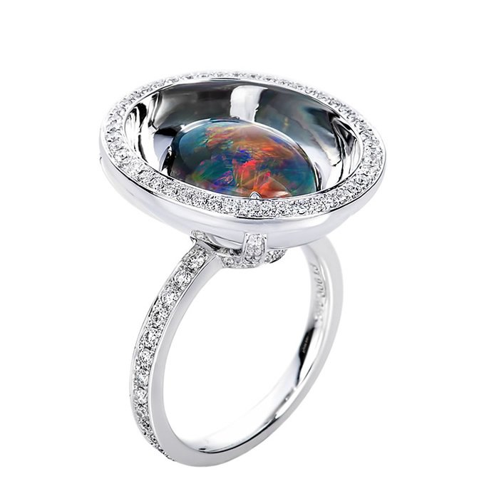Silver ring with a large oval black opal gemstone and small diamonds around the setting.