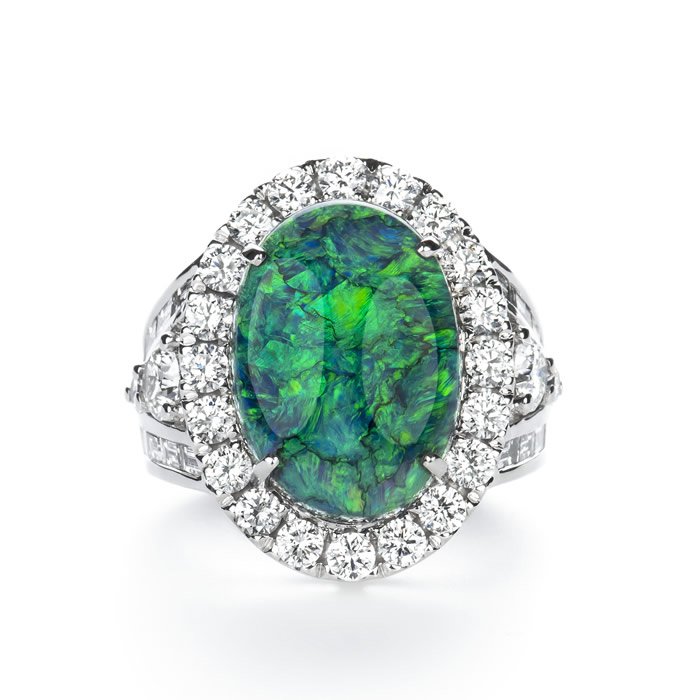A silver ring with an oval-shaped green and blue opal gemstone surrounded by a halo of small diamonds.