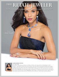 Magazine cover featuring a young woman with long dark hair wearing a strapless black dress and jewelry, including earrings, a necklace with a large blue pendant, and rings, holding her arms crossed in front of her.