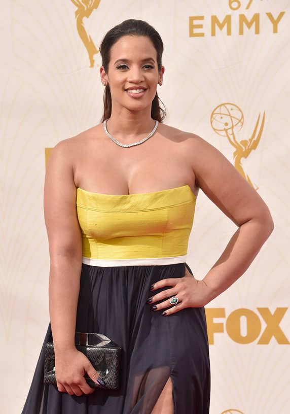 Woman in yellow and black strapless dress holding a clutch at an award event.