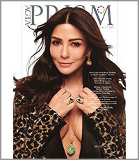A woman with long, dark hair wearing a leopard print jacket, gold jewelry, and a black top, posing for a magazine photo.