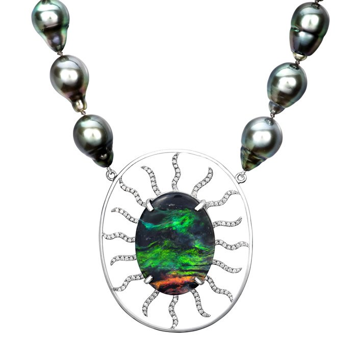 A necklace with large dark gray pearls and a pendant featuring a black and green opal surrounded by a silver setting with snake design accents.