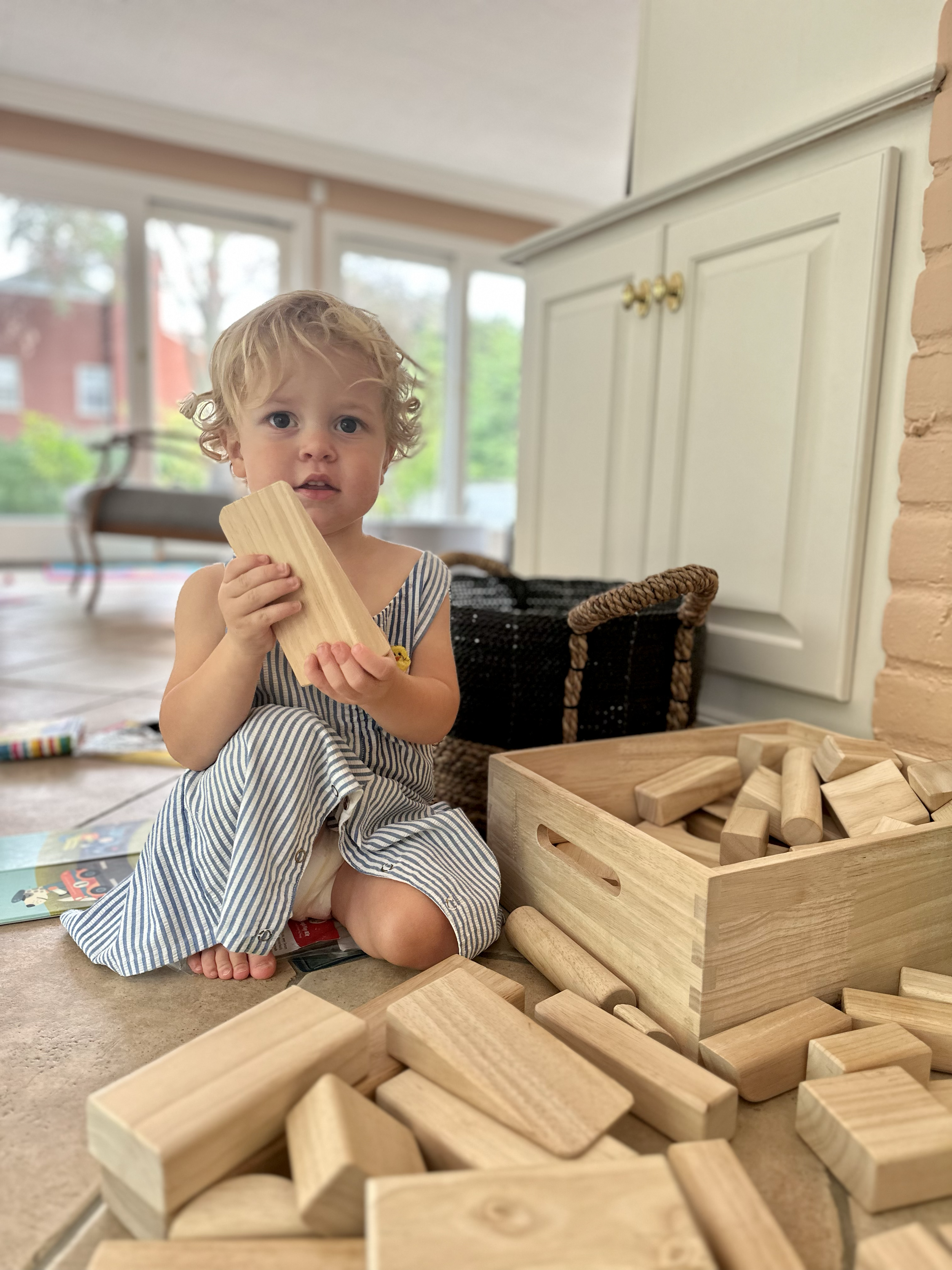 Mother and daughter sitting on a carpet playing with building blocks in a living room.