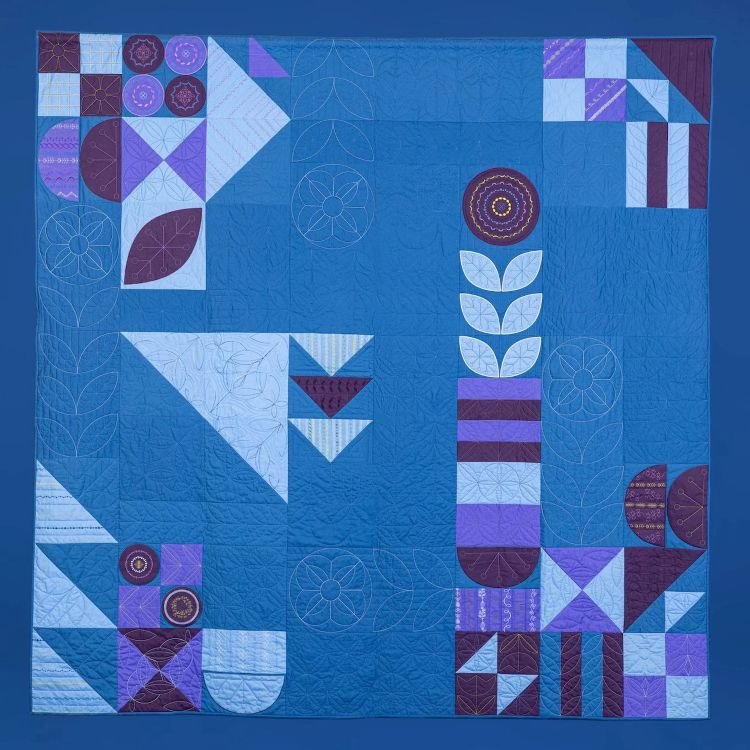 Twilight Garden quilt by BERNINA featuring modern geometric and floral blocks in shades of blue and purple.