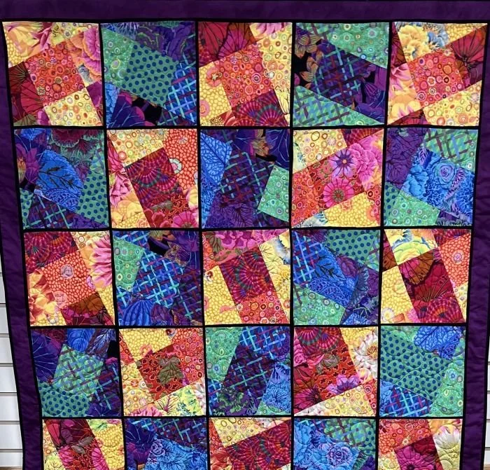 Kaleidoscope quilt top featuring vibrant multicolored fabric blocks arranged in a dynamic geometric pattern.