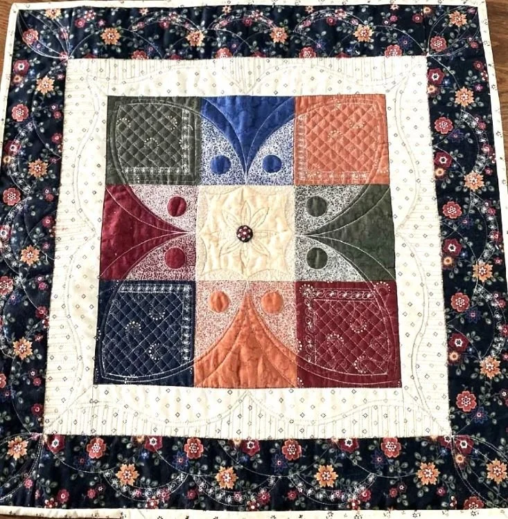 Quilt block sample featuring curved and straight ruler quilting designs stitched across pieced sections and borders.