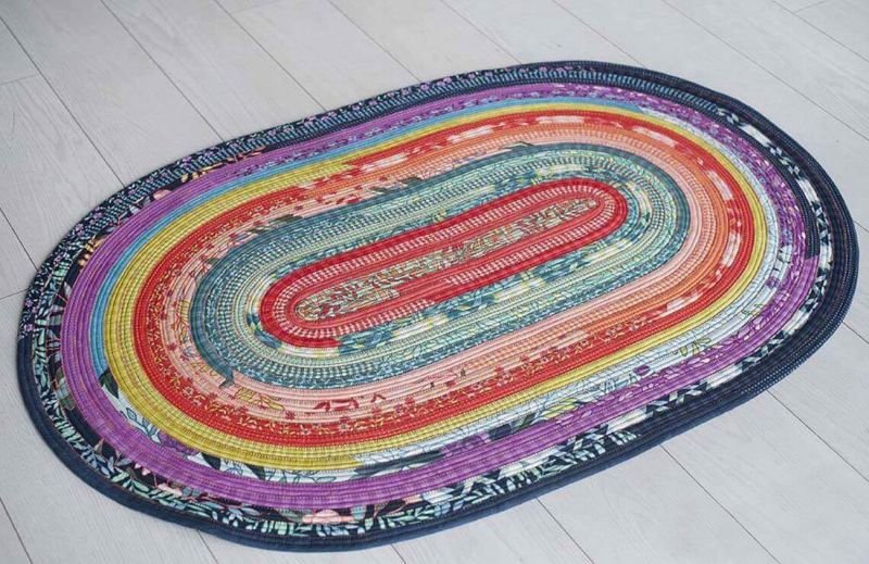 Jelly roll rug project featuring an oval rug made from multicolored fabric strips and cotton batting