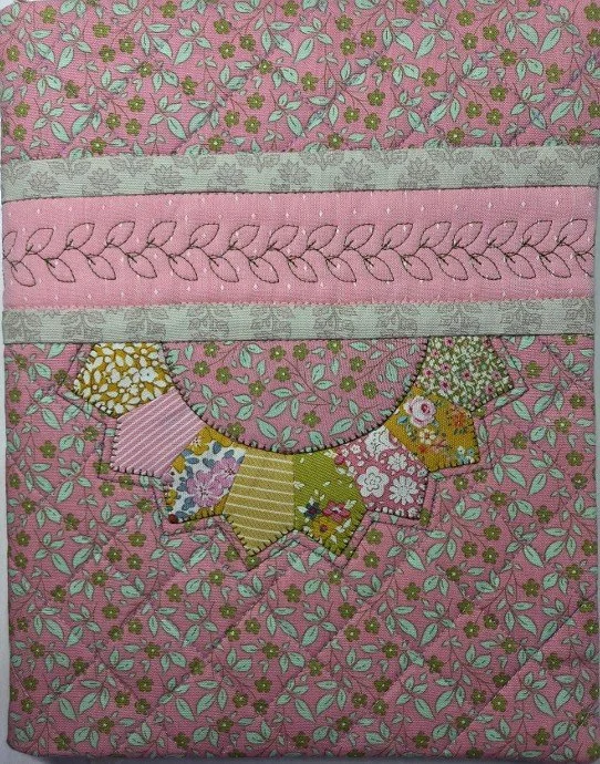 Handmade pink and green fabric notebook cover featuring a colorful Dresden plate appliqué design, decorative stitching, and floral-patterned fabric.