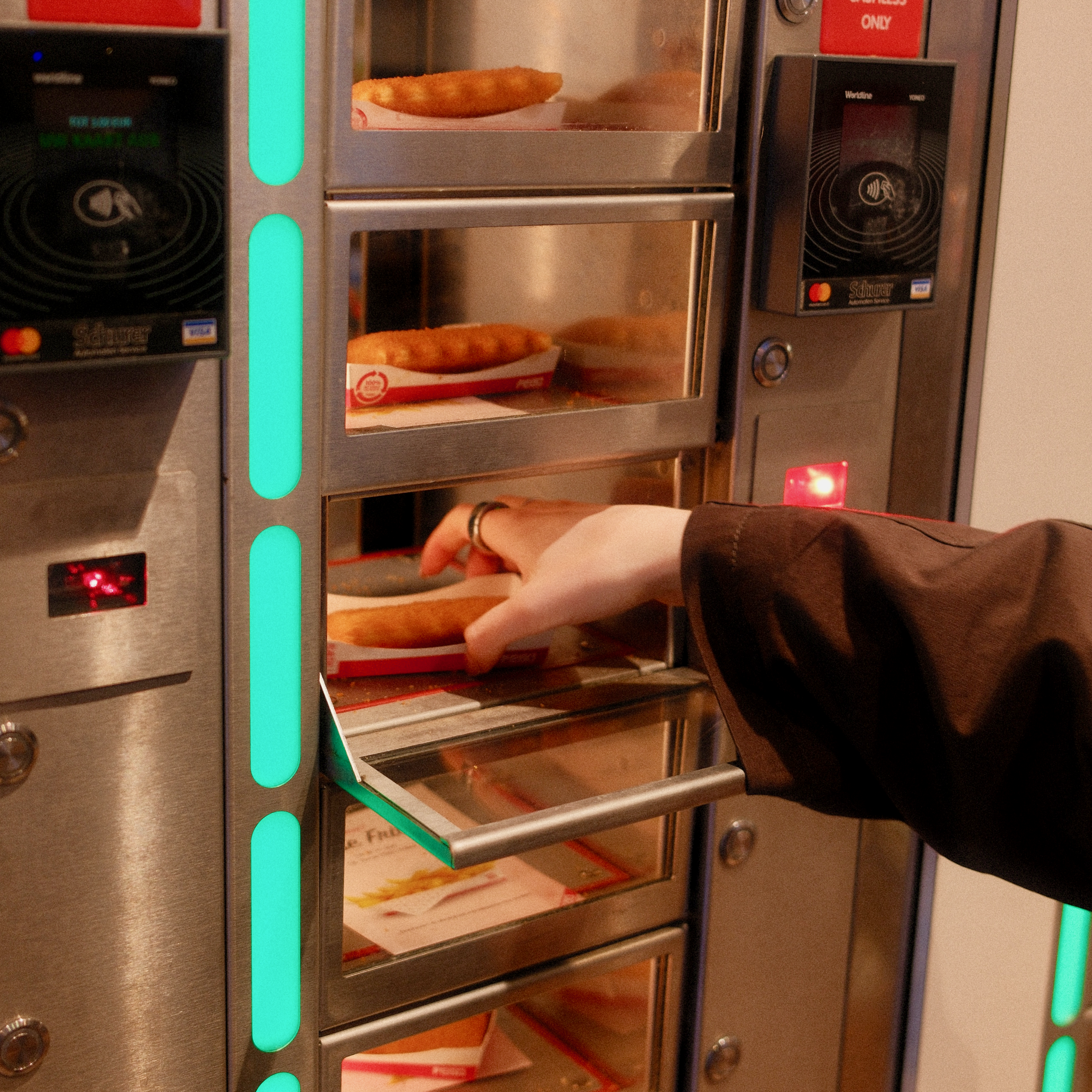 hand greift in einem snackautomaten nach frittiertem käse zwischen kleinen verpackten snacks.