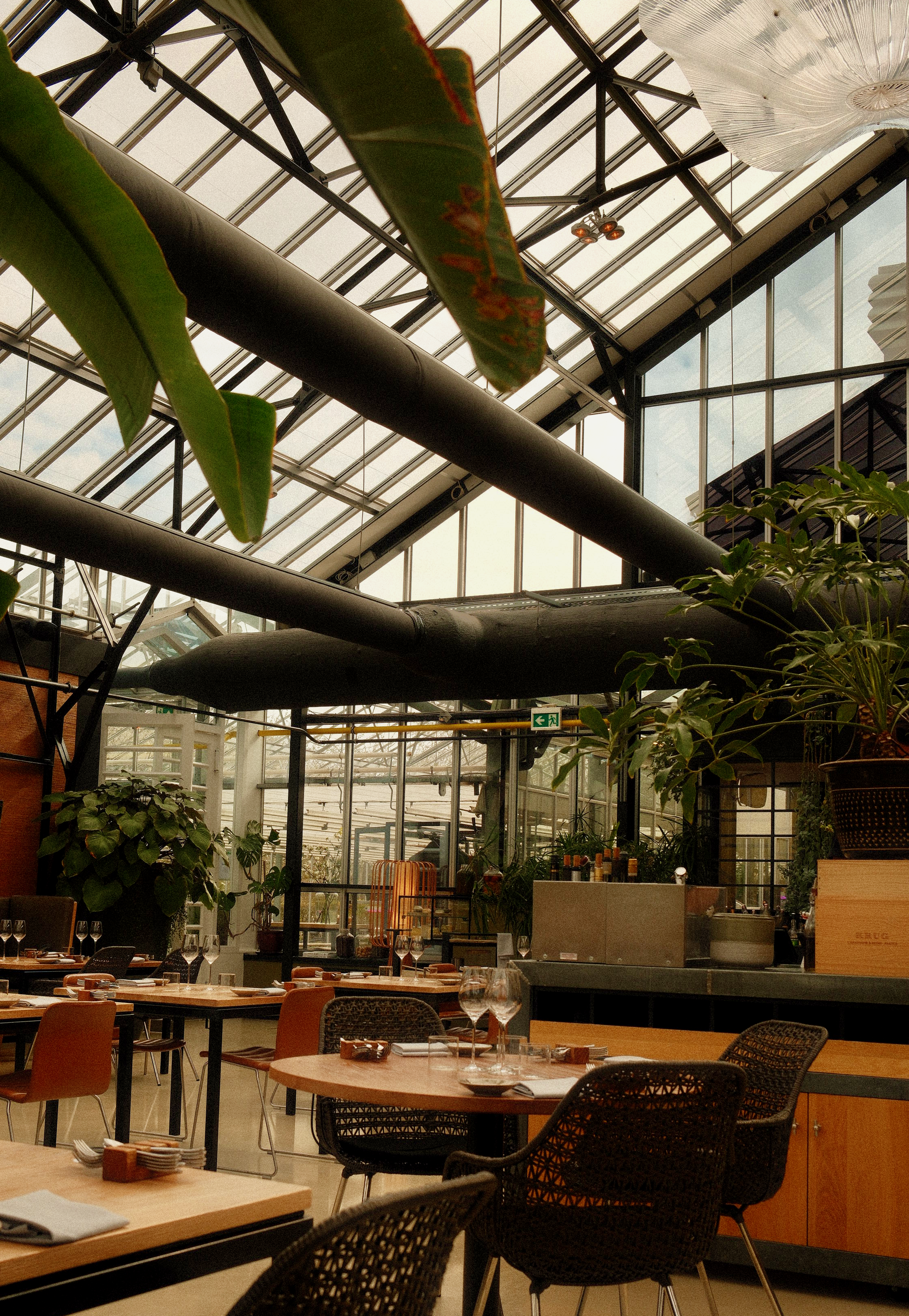 lichtdurchfluteter restaurantbereich mit glasdecke und stilvoll gedeckten tischen zur mittagszeit.