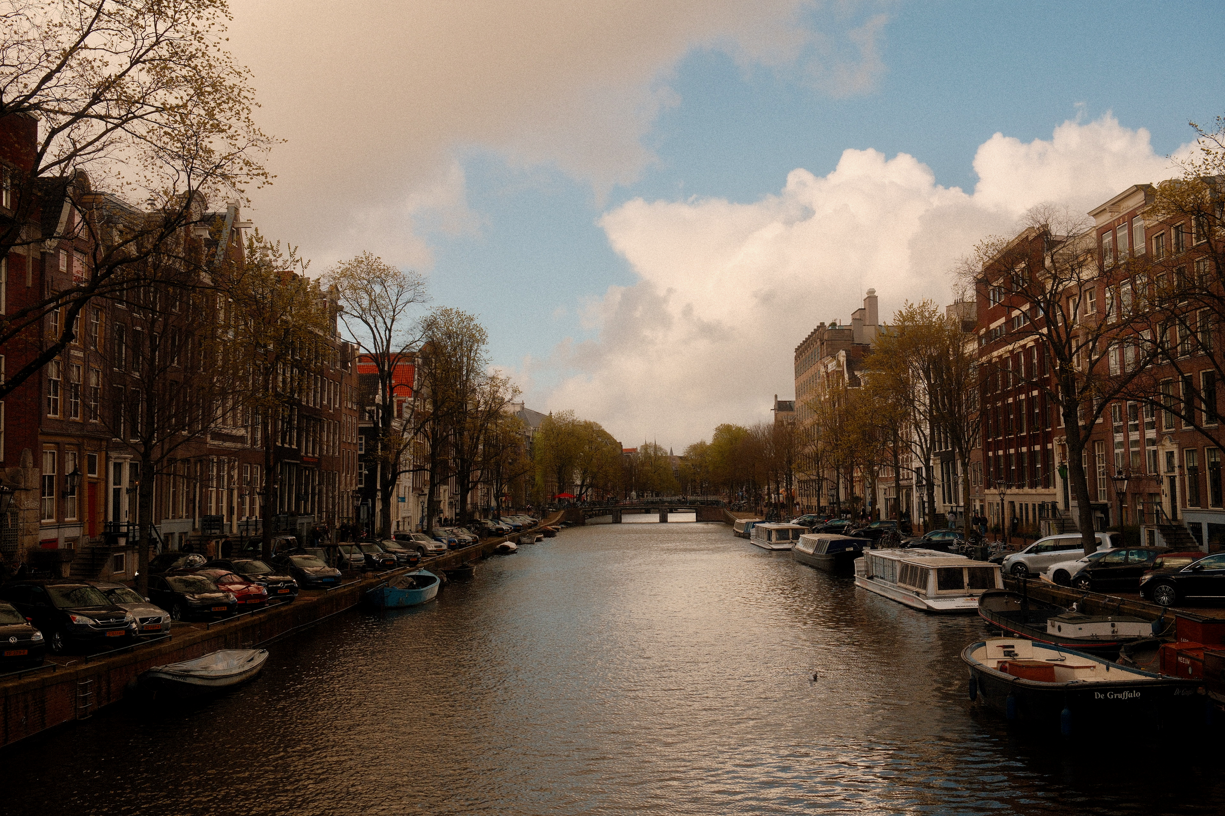 blick auf einen amsterdamer kanal mit historischen giebelhäusern auf beiden seiten und ruhigem wasser in der mitte.