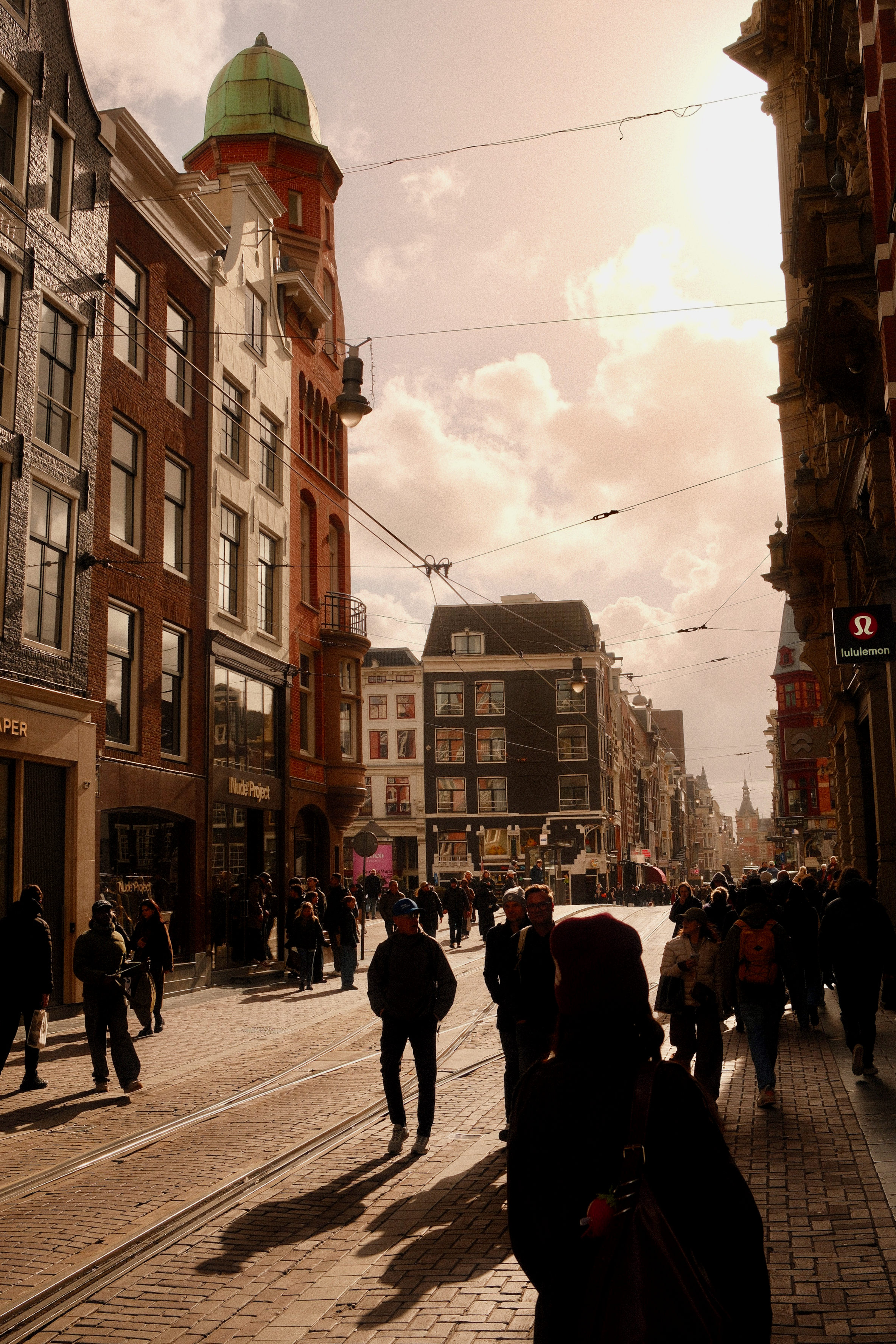 enge einkaufsstraßen nahe des blumenmarktes in amsterdam mit vielen menschen, geschäften und dichter bewegung zwischen den gebäuden.