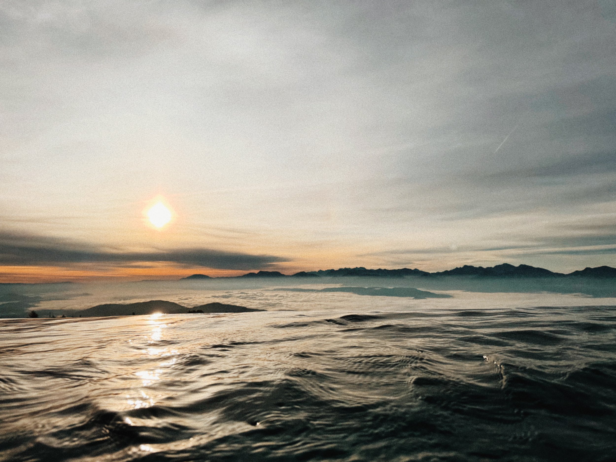 unendlichpool am feuerberg mit wolken im tal und sonne über der geschlossenen wolkendecke