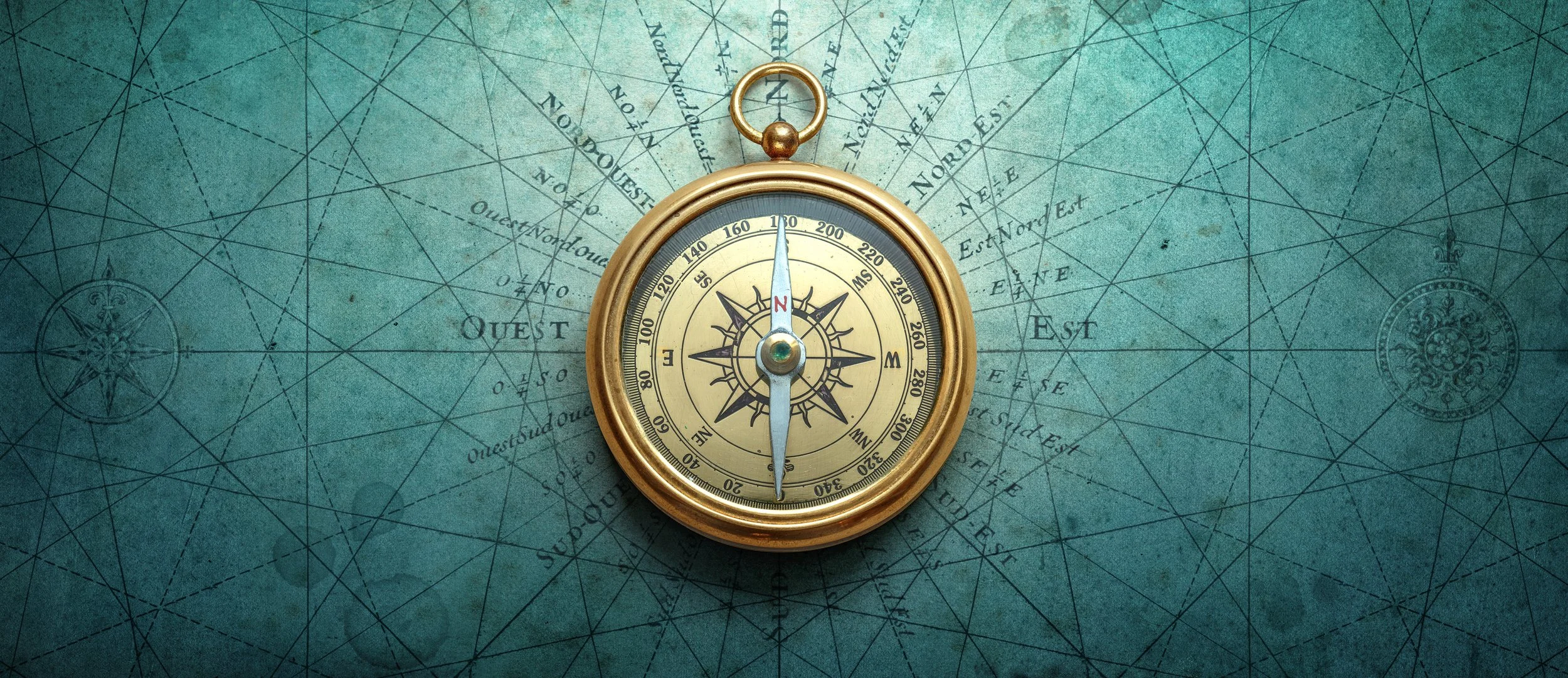Golden compass on a teal vintage map background with faint navigation lines and directional markings.