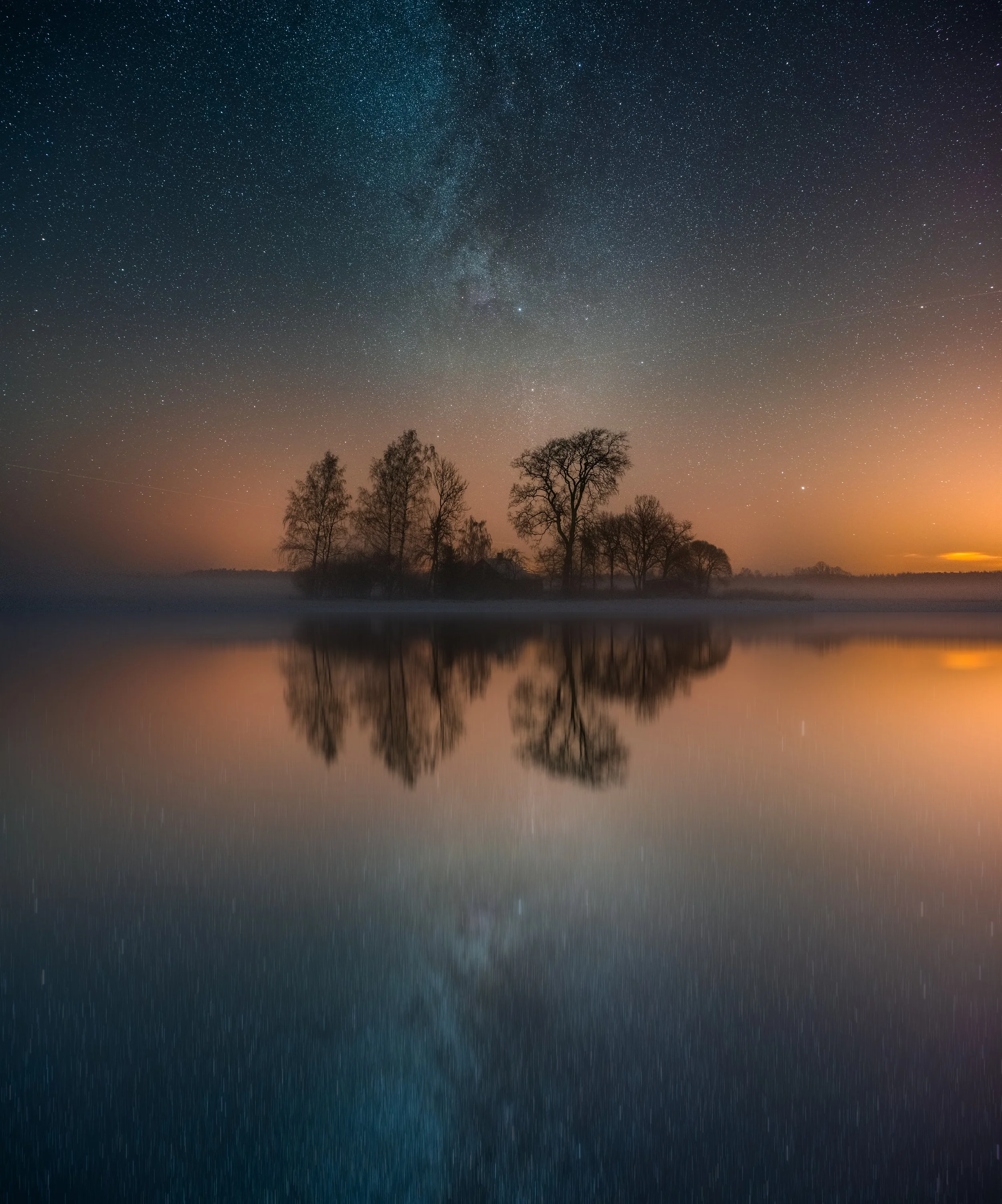 Twilight landscape of trees mirrored on a calm lake, evoking surrender, depth, and the quiet beauty of transformation.
