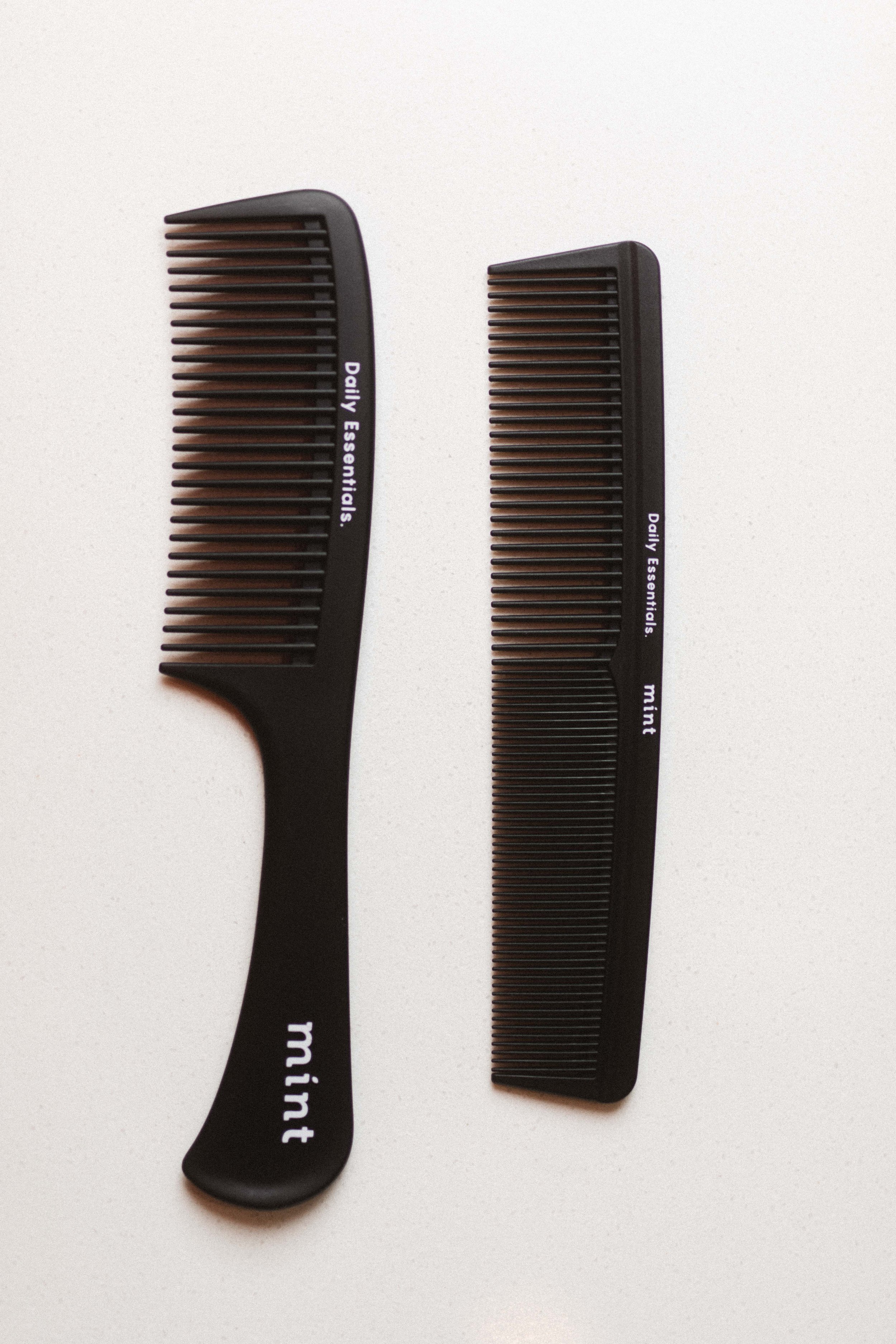 Two black hair combs on a white background, one with a handle labeled ‘mint’ and the other labeled ‘daily essentials,’ positioned horizontally.