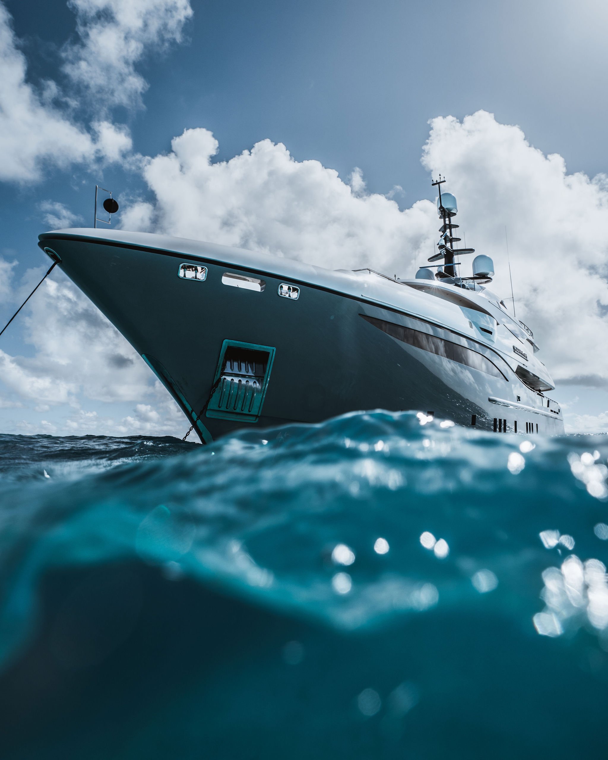 A large luxury yacht in the ocean with a partly cloudy sky in the background.