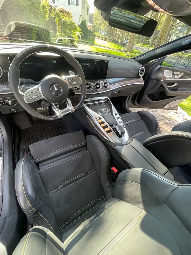 Interior of a luxury Mercedes-Benz vehicle, showing the driver's seat, steering wheel, dashboard, center console, and front passenger seat.