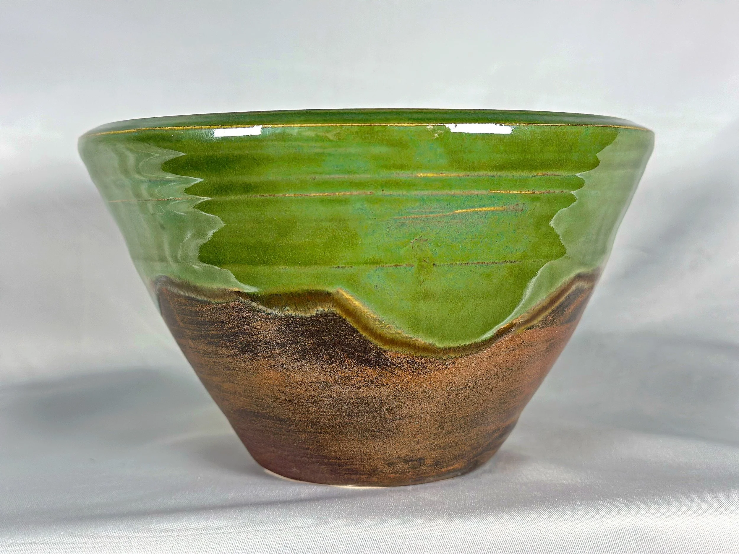 Ceramic bowl with a glaze pattern resembling a landscape, featuring green, brown, and gold hues.