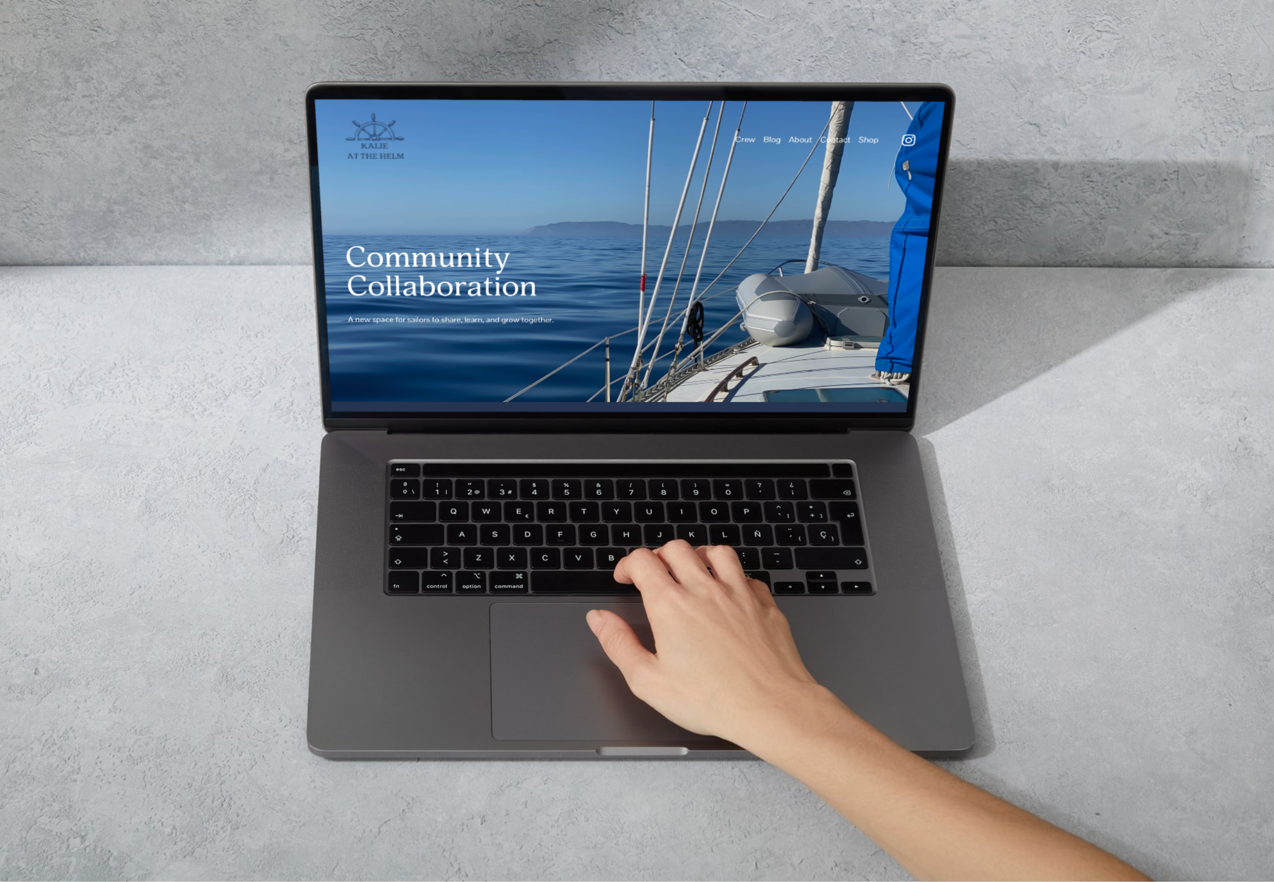Open laptop on a light gray surface displaying a website with a sailing boat image and the text "Community Collaboration".