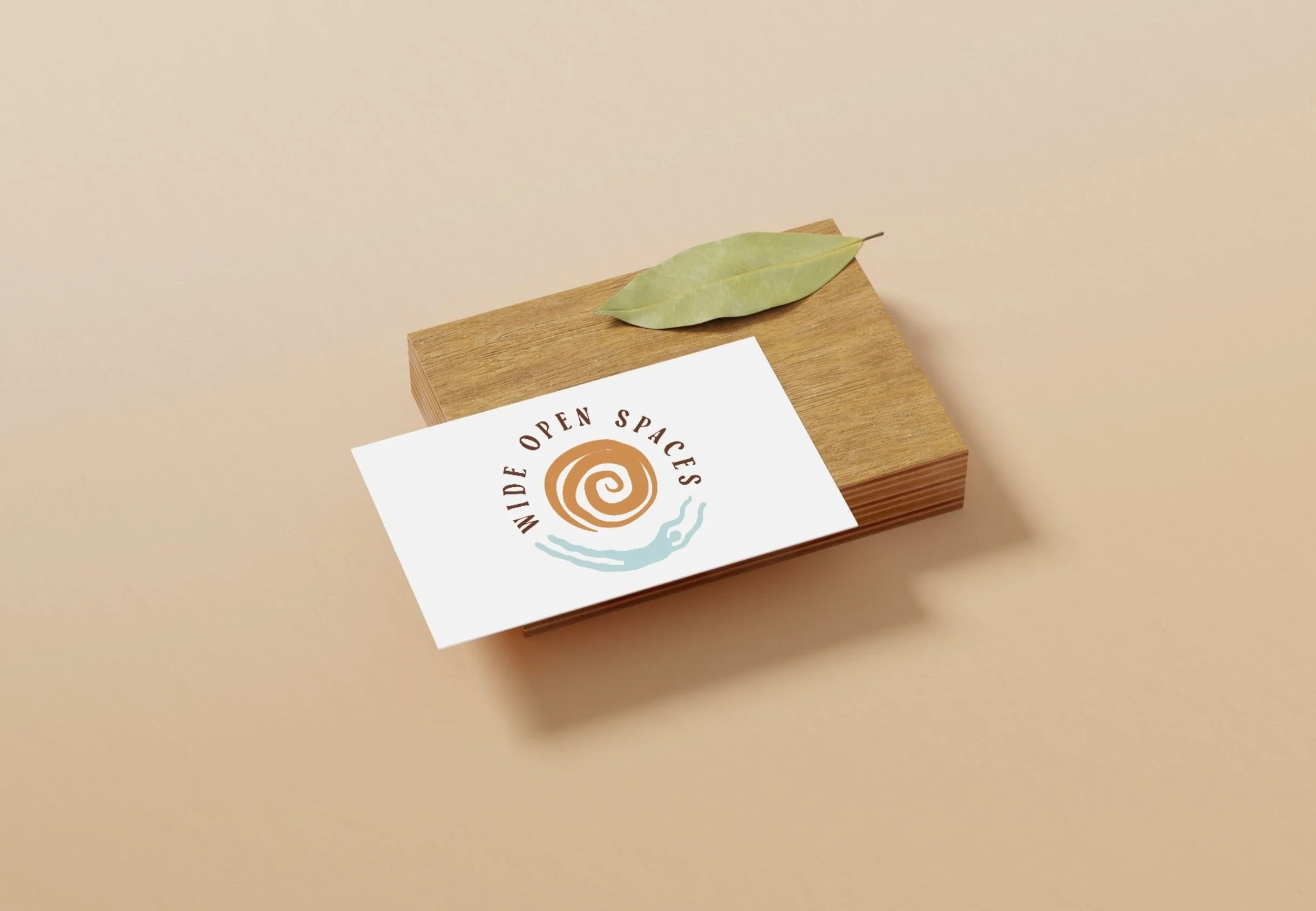 A white card with the logo and text "Made Open Spaces" on it, placed on a wooden block, with a green leaf on top, set against a beige background.