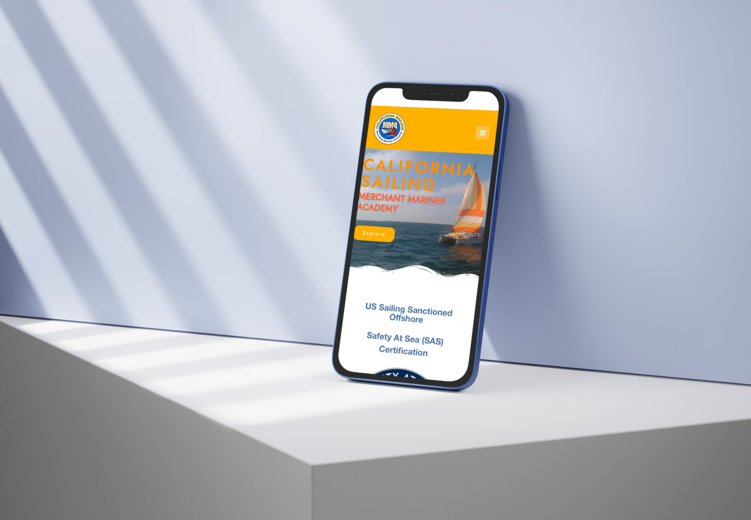 A smartphone lying on a white surface displaying a webpage for California Sailing, featuring a sailboat on the water and navigation options.