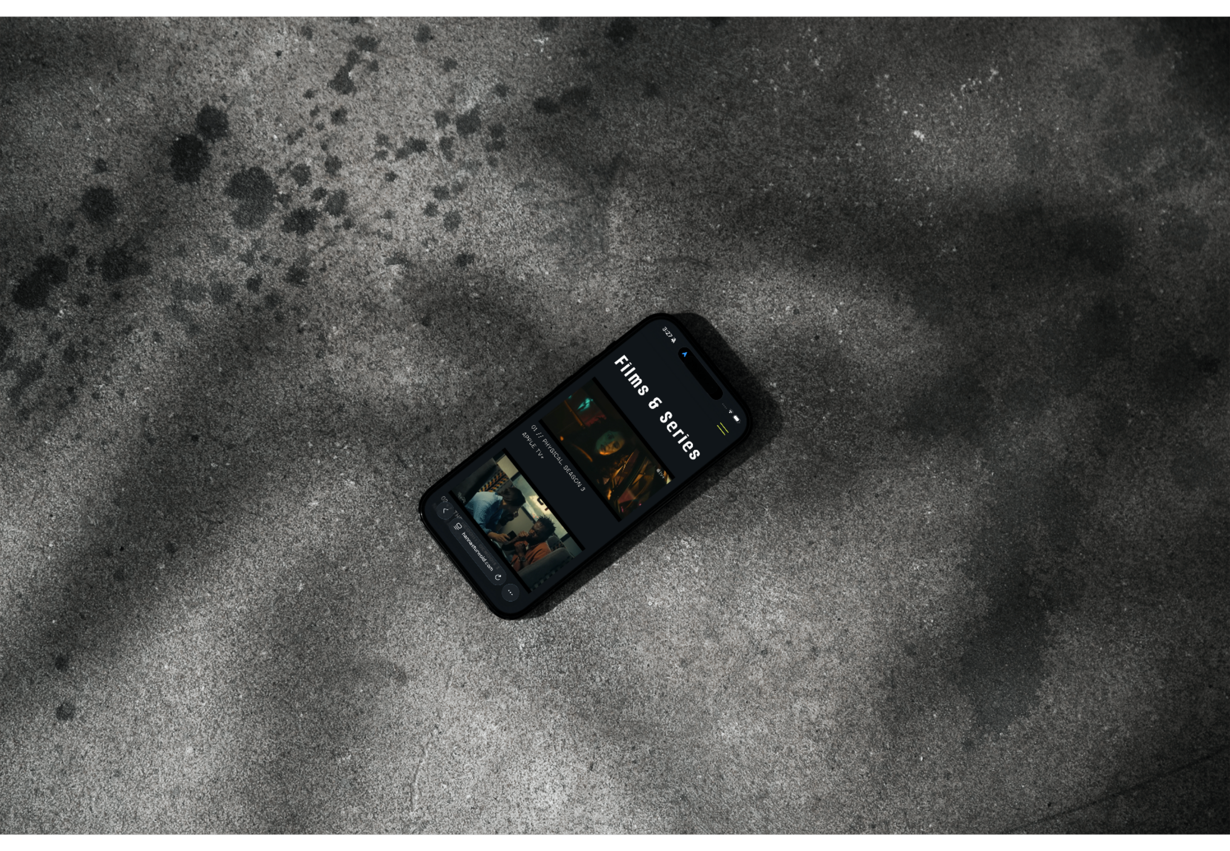 A smartphone displaying a streaming app with films and series, lying on a sandy surface with dark spots.