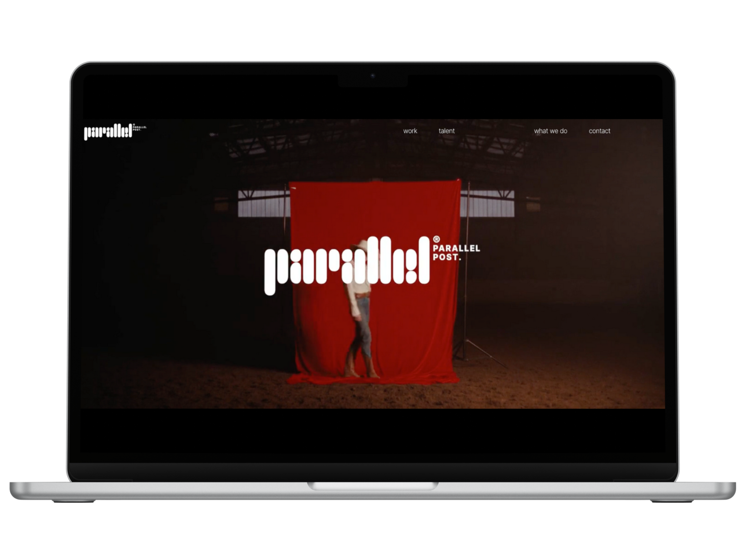 A person standing in front of a red backdrop inside a dark, warehouse-like space, with the logo 'parallel' and the text 'PARALLEL POST' superimposed on the image.
