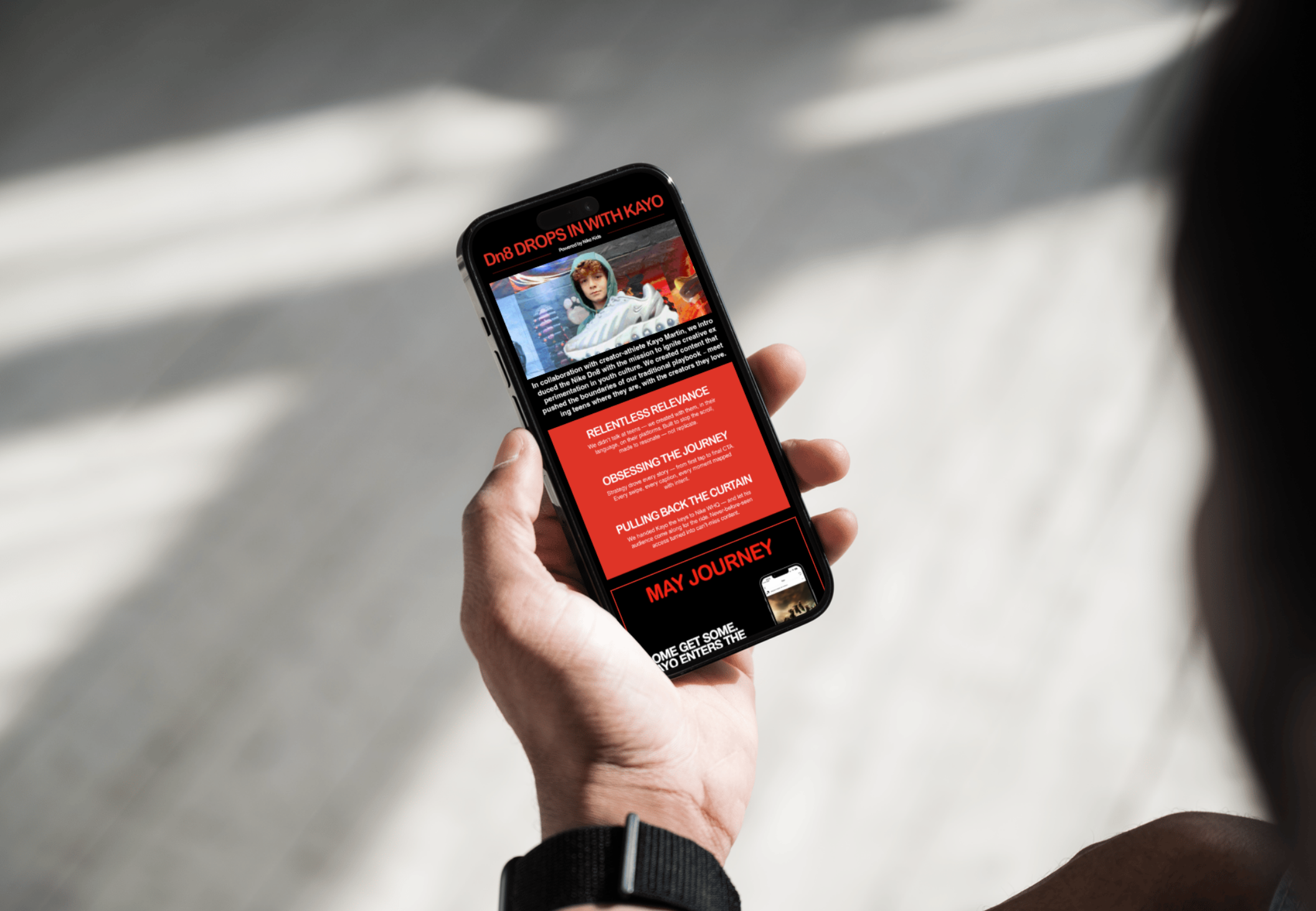 Person holding a smartphone displaying a website or app with red and black themed text about Kayo