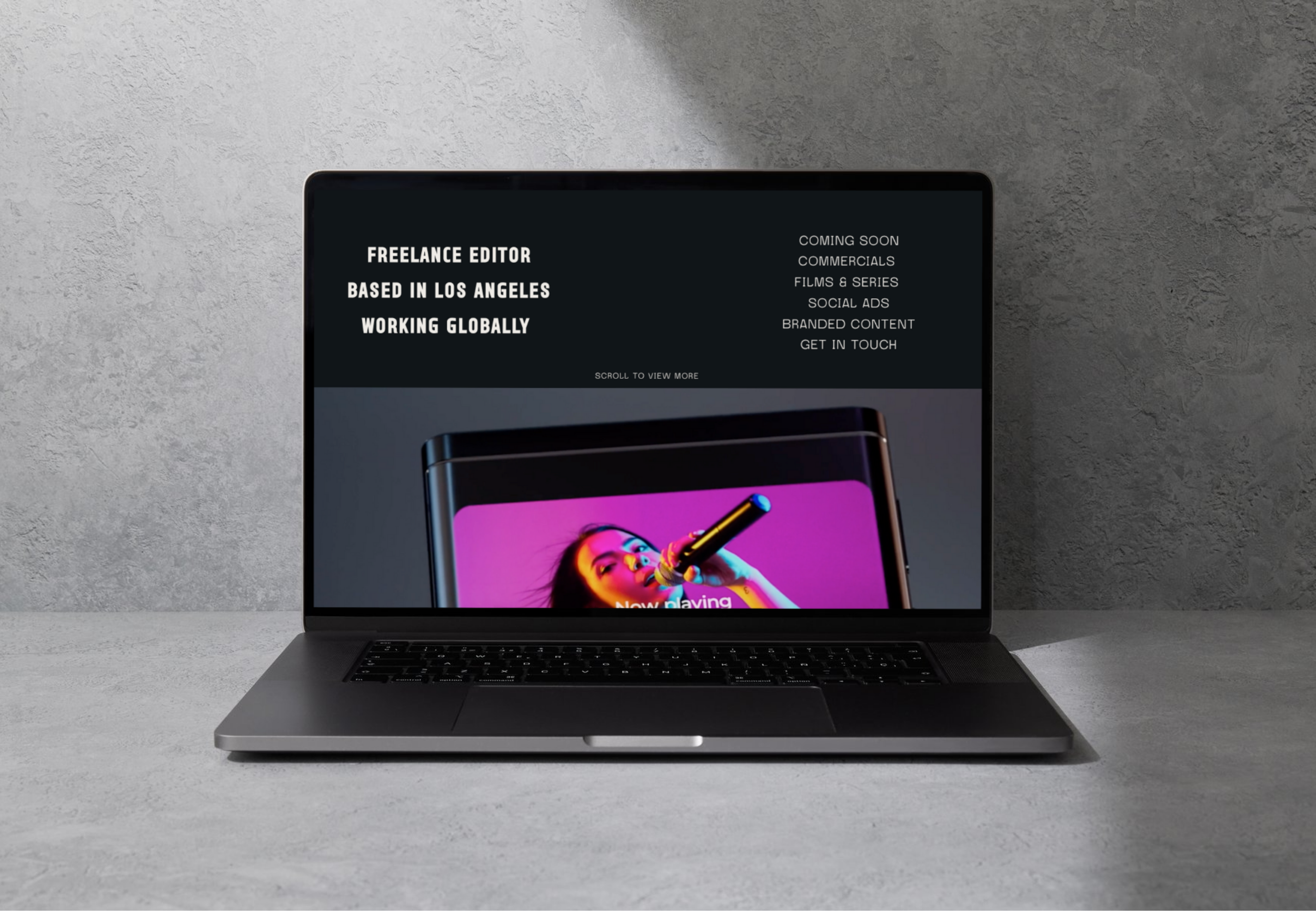 A laptop displaying a website with text about a freelance editor based in Los Angeles, working globally, and an image of a woman performing with a microphone on the screen.
