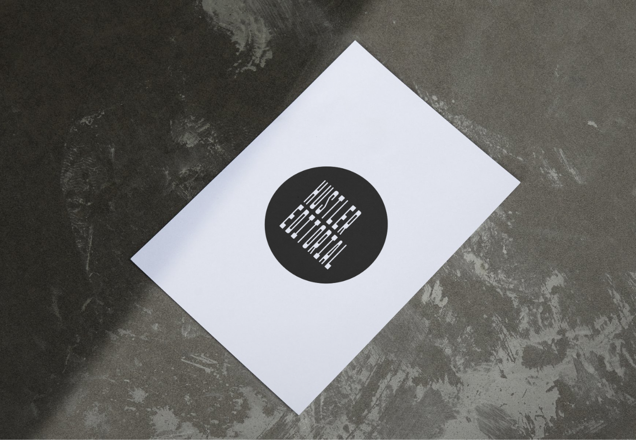 A sheet of paper with the text "HISTER EDUARDO" printed in white on a black circular background, placed on a gray concrete surface.