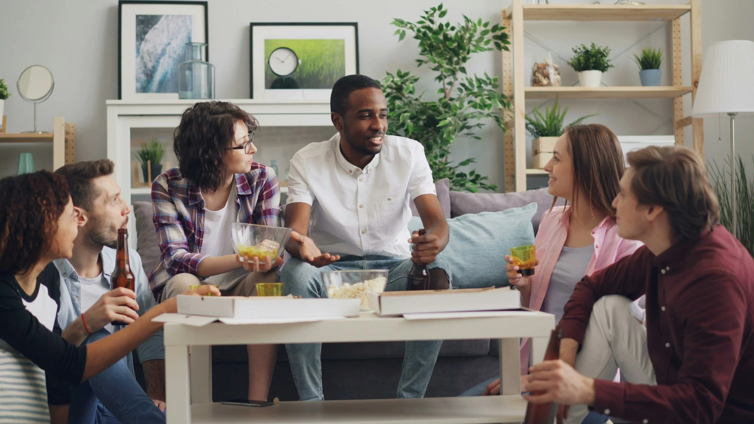 A group of people gathered around a table celebrating in a cozy living room.
