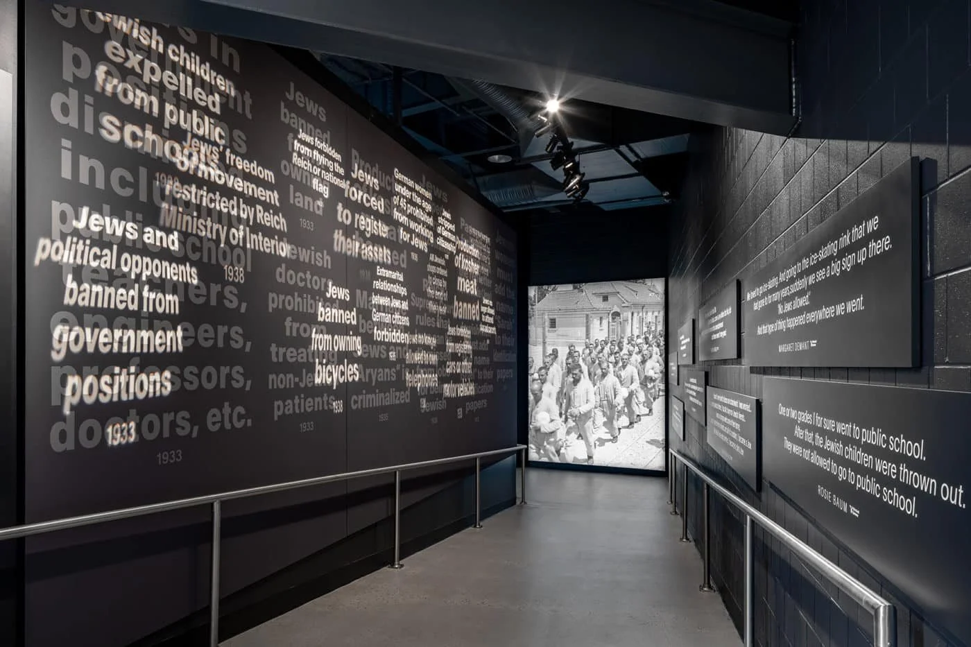 An exhibit at the Zekelman Holocaust Center in Michigan, depicting black walls with white text which describes anti-Jewish laws passed in Germany during the 1930s
